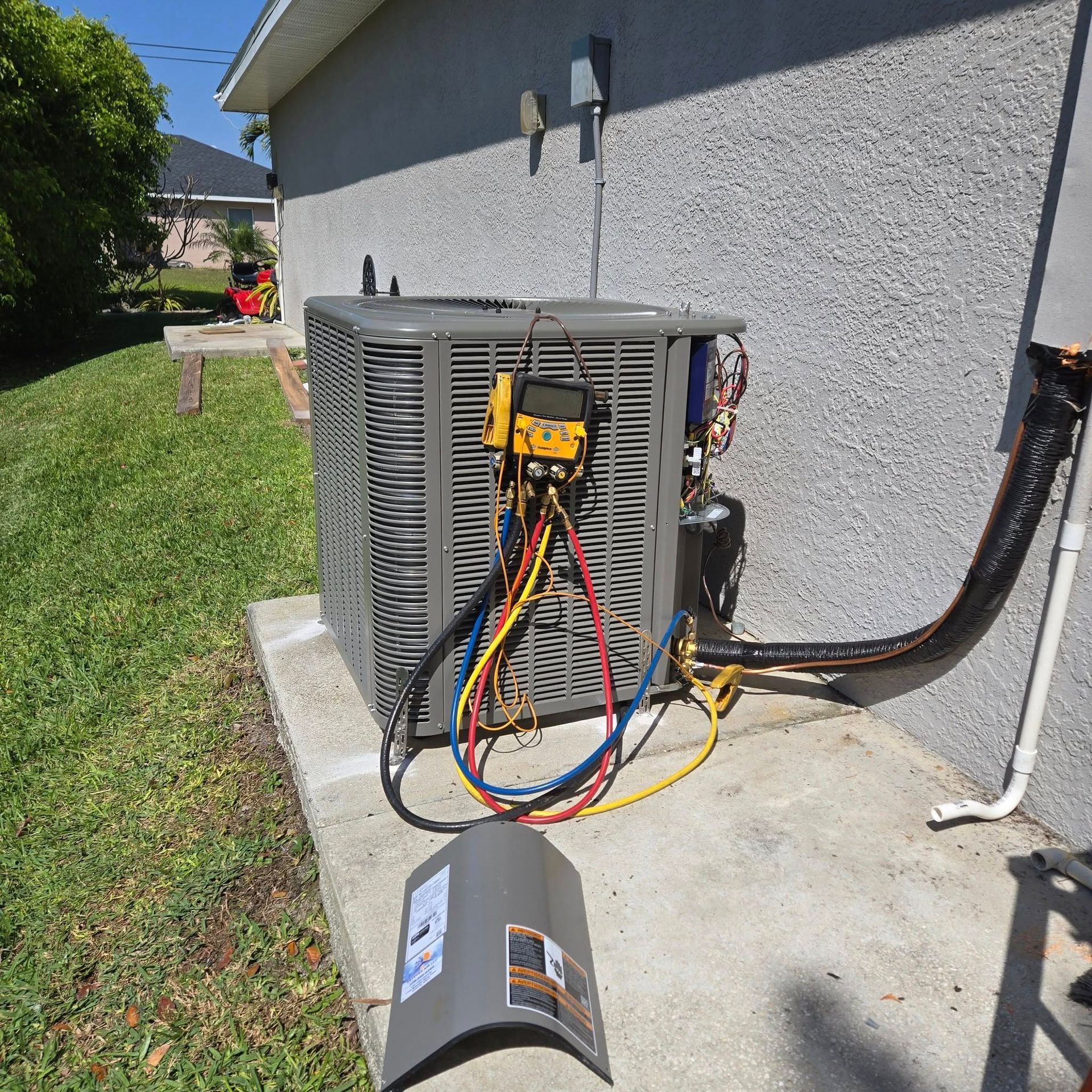HVAC unit outside a home being serviced with gauges and hoses attached.
