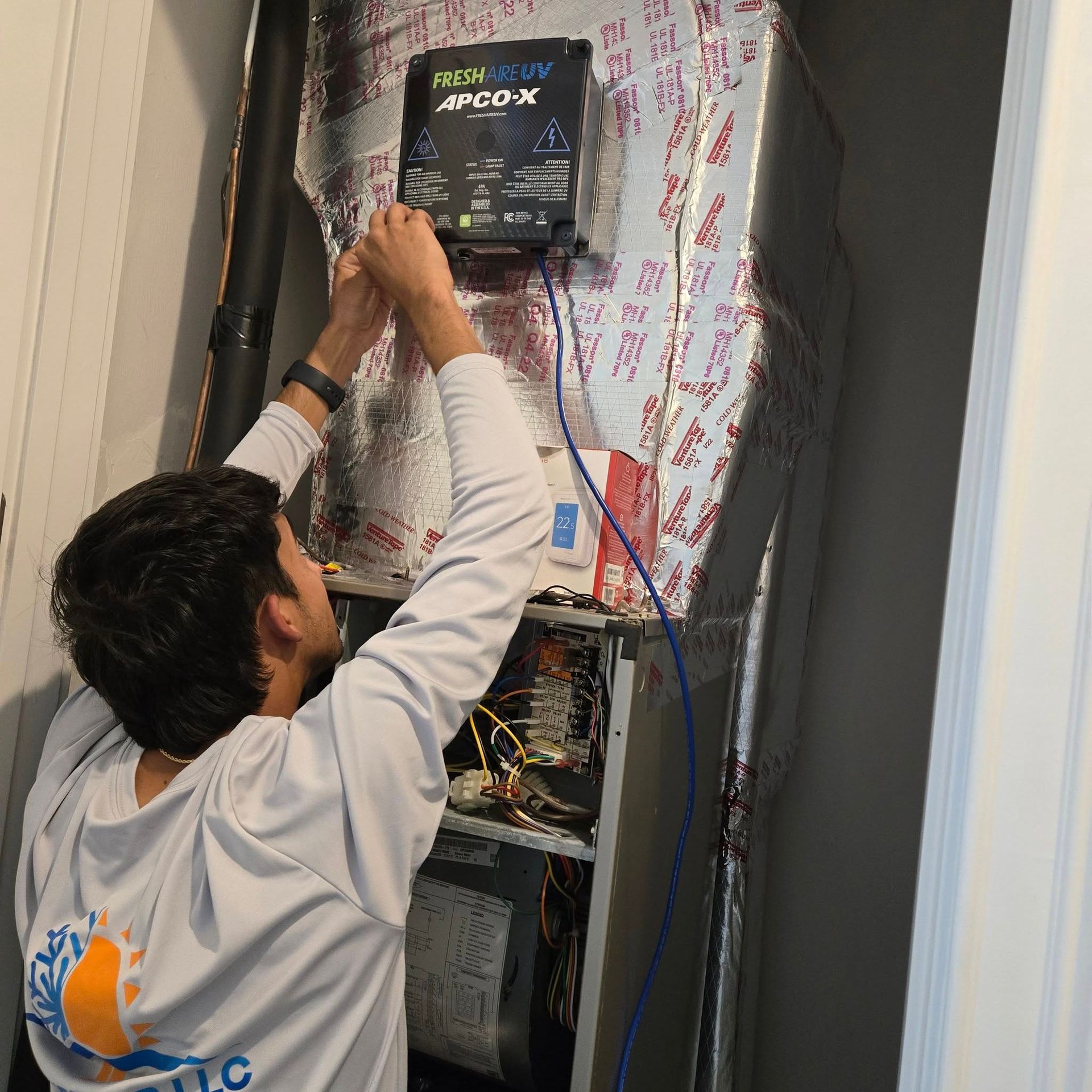 HVAC technician working on an air handler unit in a utility closet.