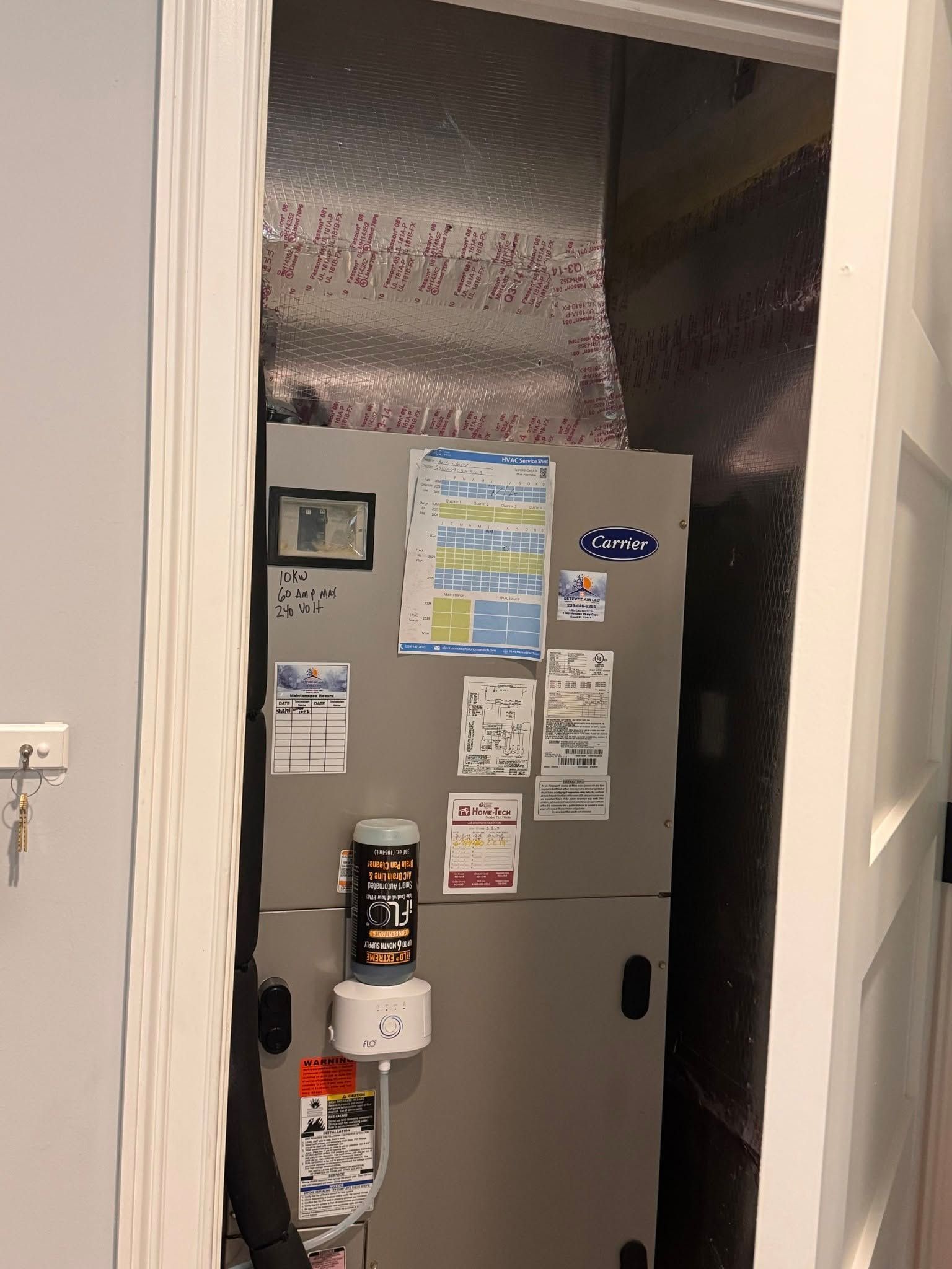 A furnace is partially visible in a doorway. It's gray with stickers, and ductwork is above.