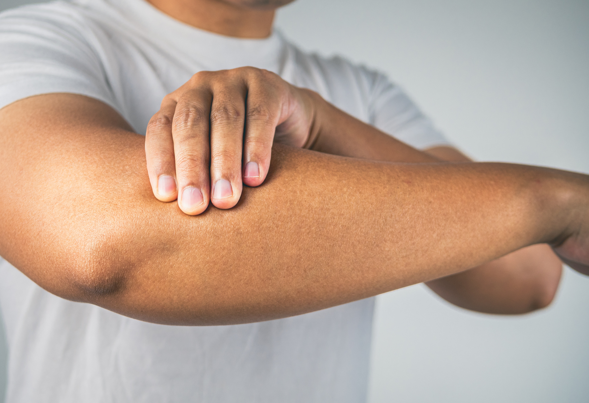 Person holding their arm, possibly experiencing pain. Skin is visible.