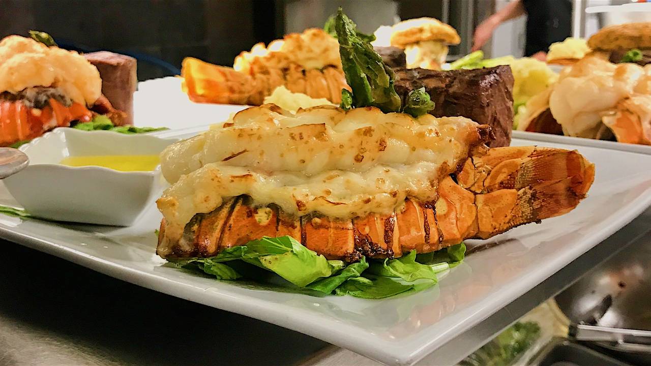 A white plate topped with a lobster tail and asparagus.