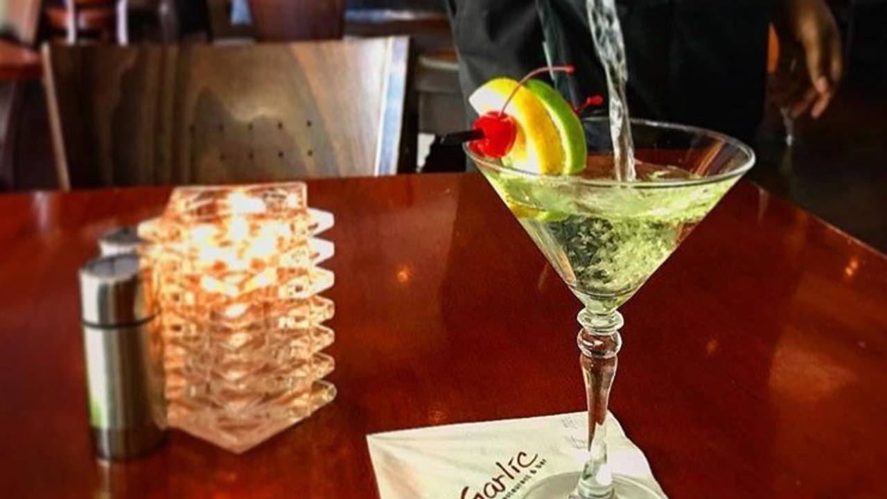 A martini is being poured into a martini glass on a table.