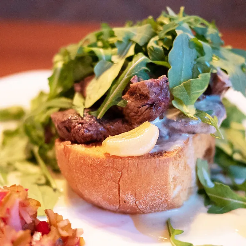A close up of a sandwich with meat and greens on a plate