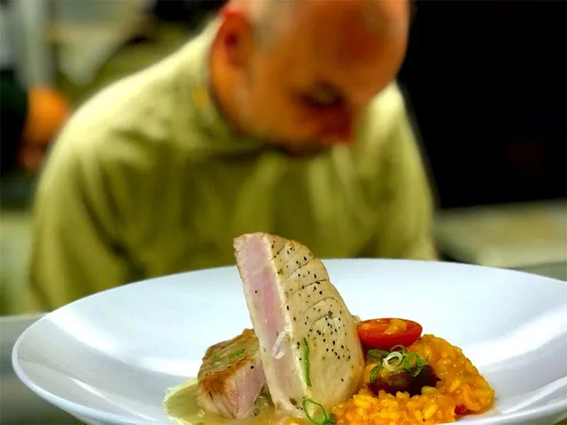 A man is looking at a plate of food with meat and vegetables