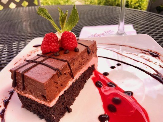 A piece of chocolate cake with raspberries on top on a white plate