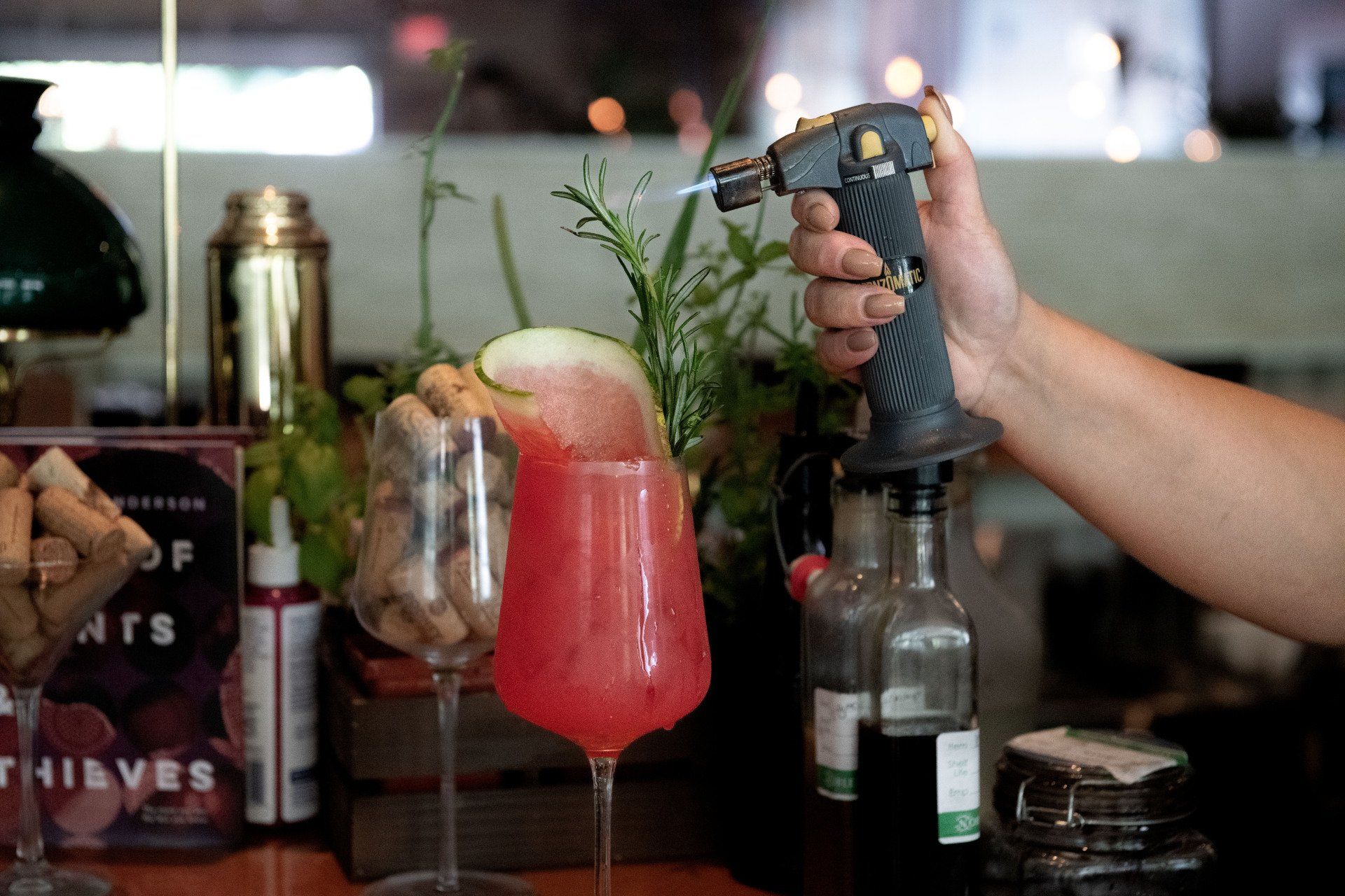 A person is spraying a drink with a torch.