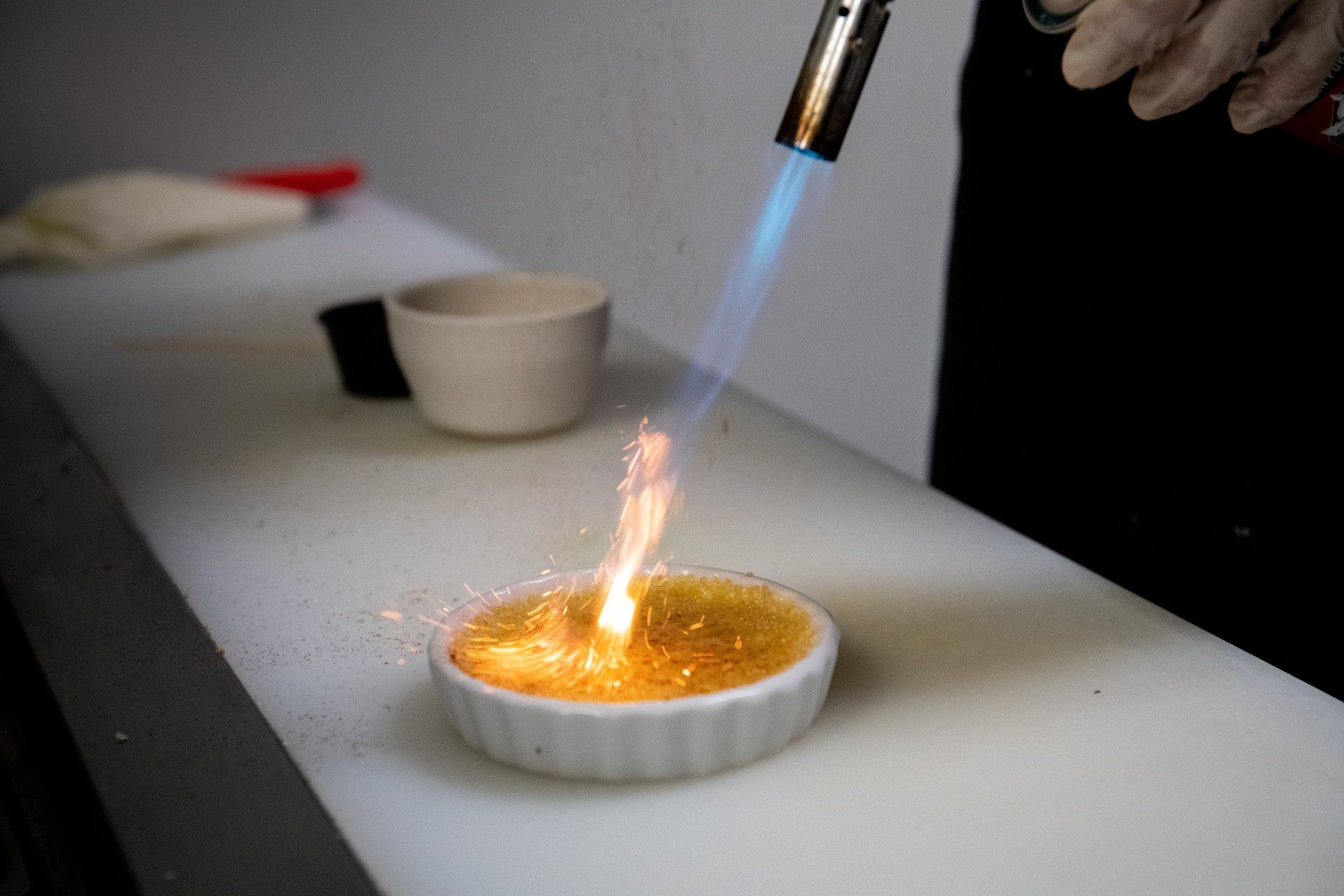 A person is lighting a dessert with a torch.