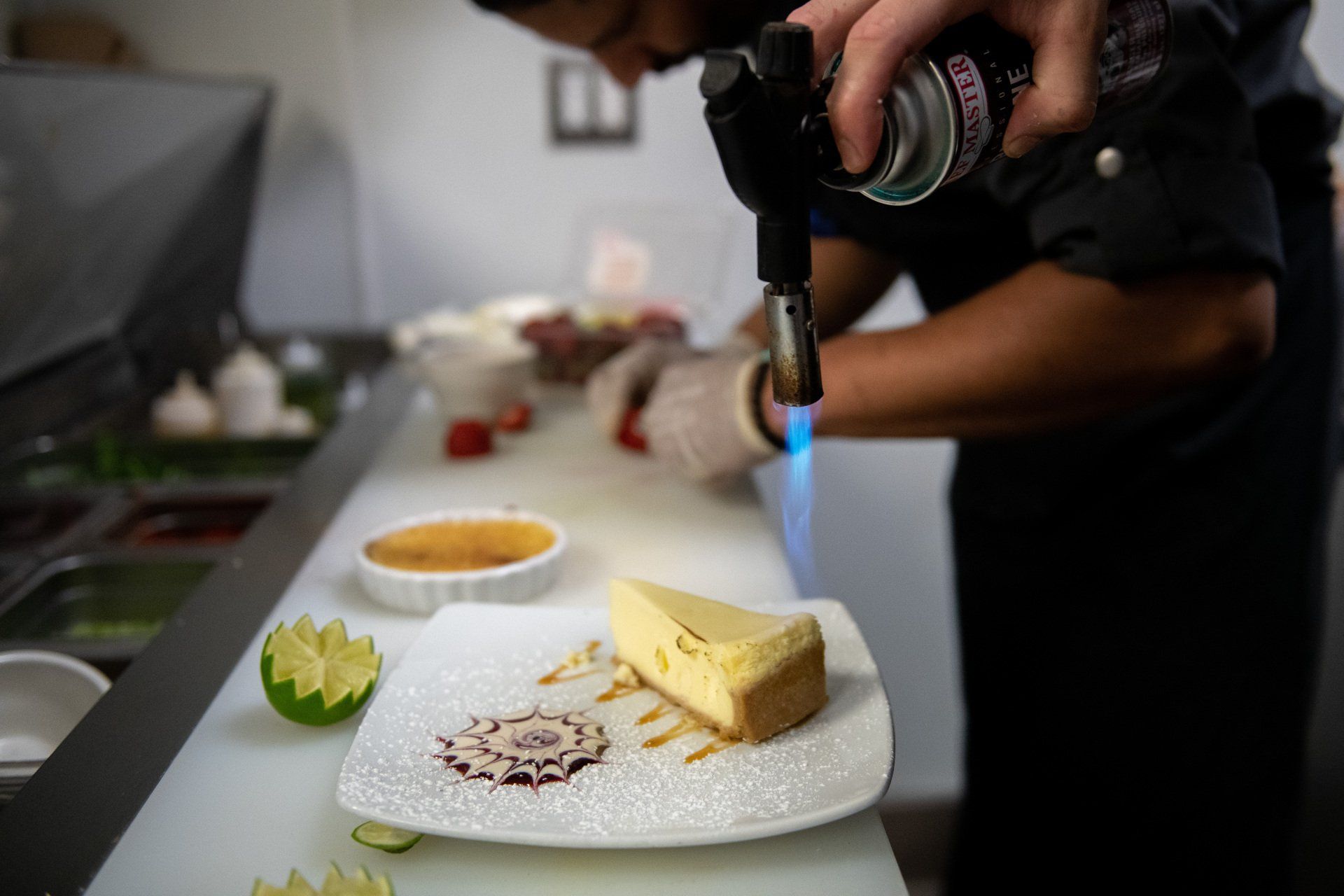 A man is lighting a piece of cheesecake on a plate.