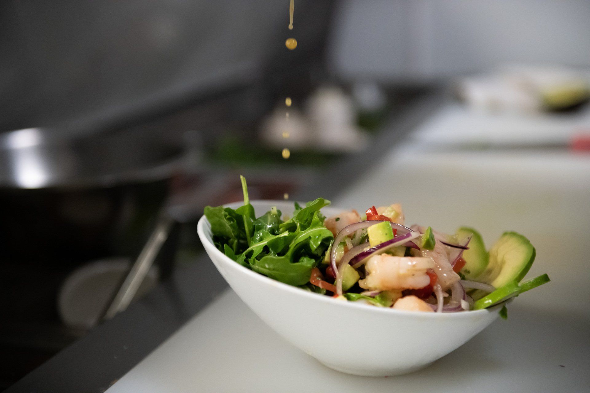 A bowl of salad with shrimp and avocado on a table.