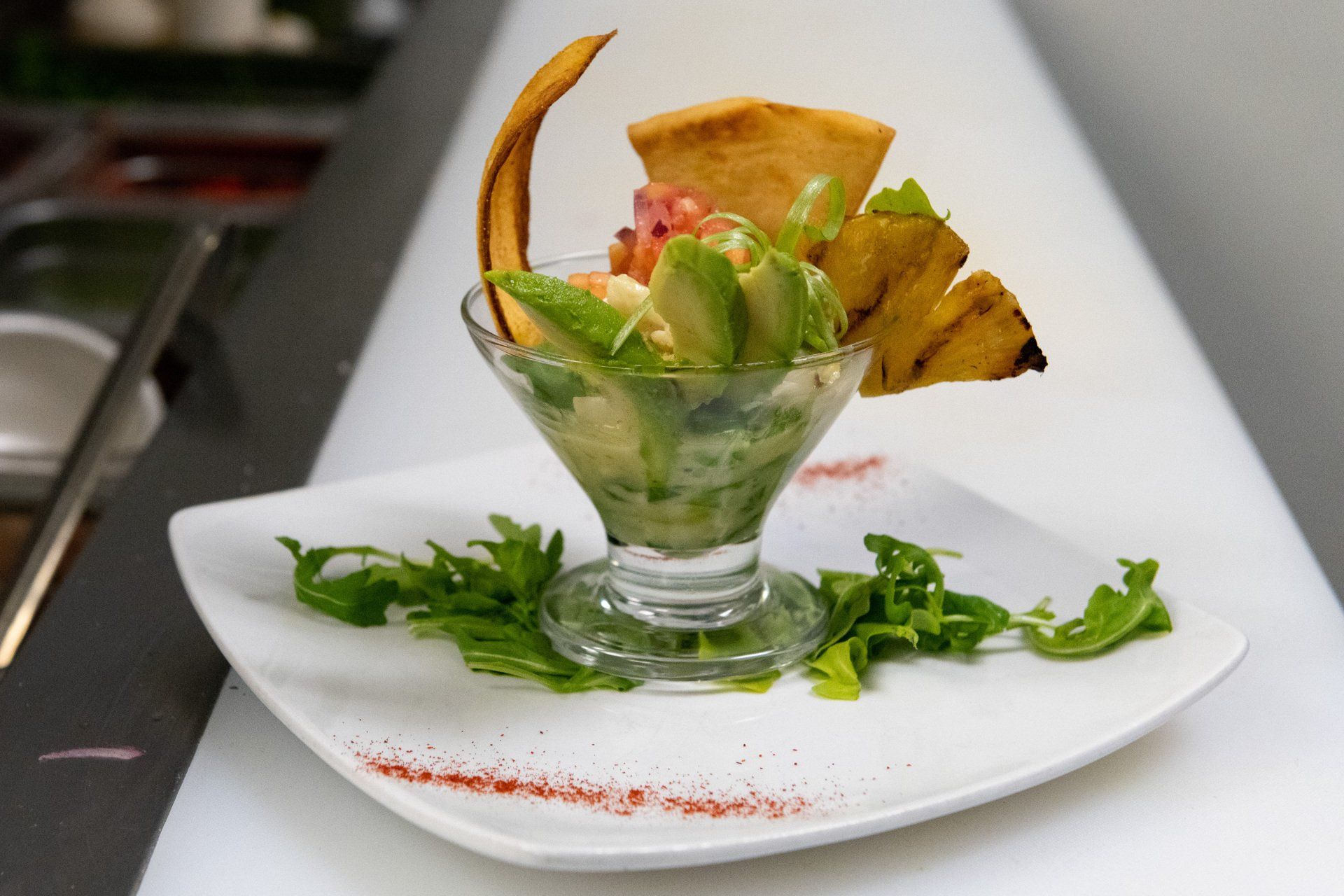 A white plate topped with a salad in a martini glass.