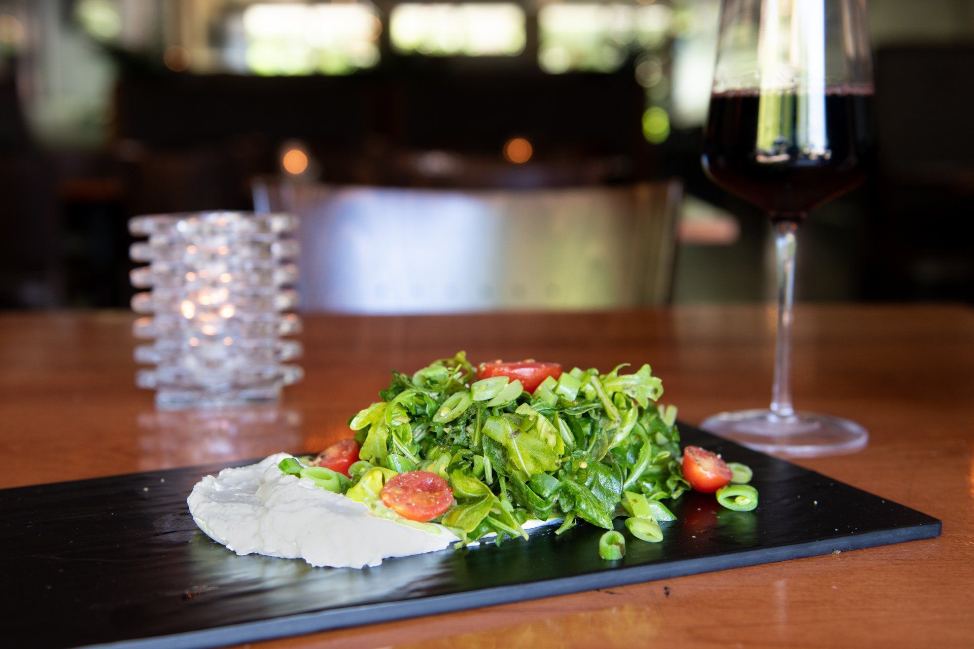 A salad and a glass of wine are on a table.