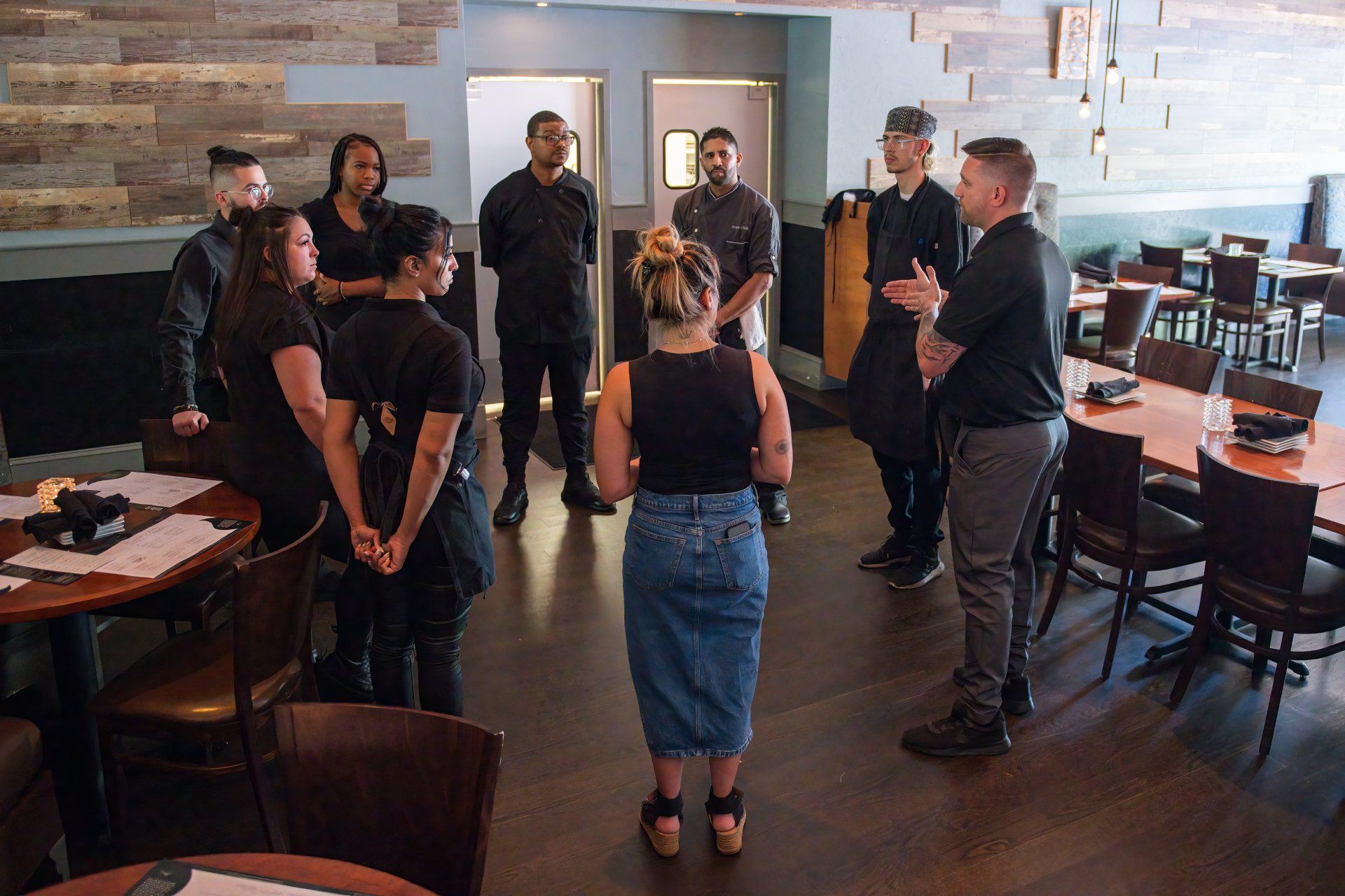 A group of people are standing in a circle in a restaurant.