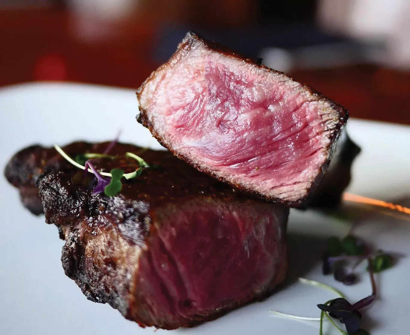 A steak is cut in half on a white plate