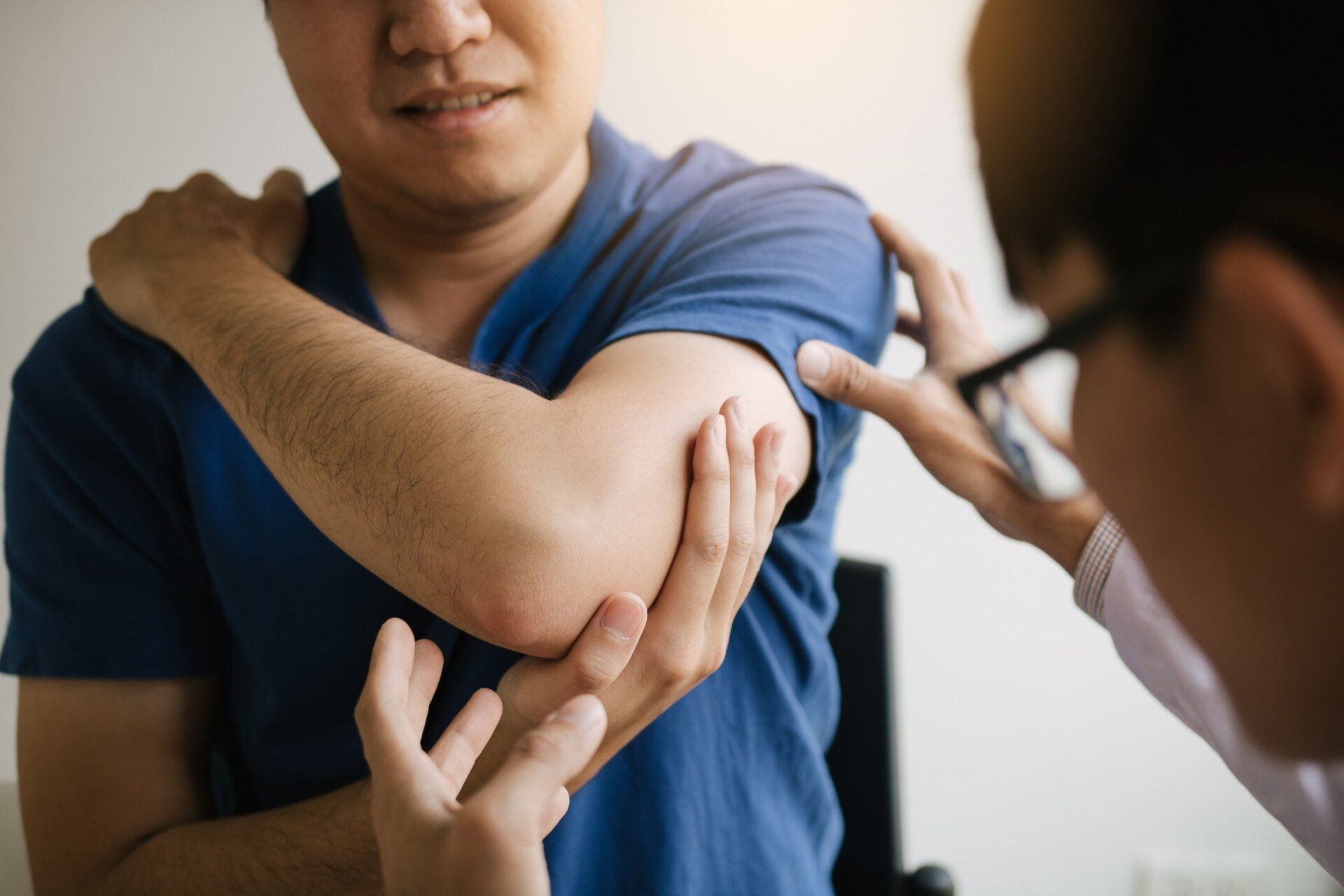 doctor examines male patient's injured arm