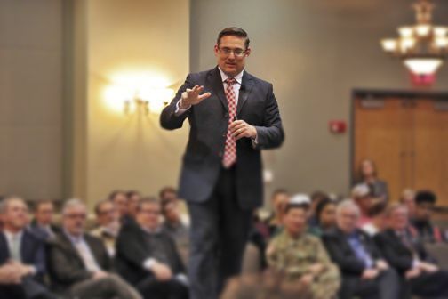 A man in a suit and tie is standing in front of a crowd