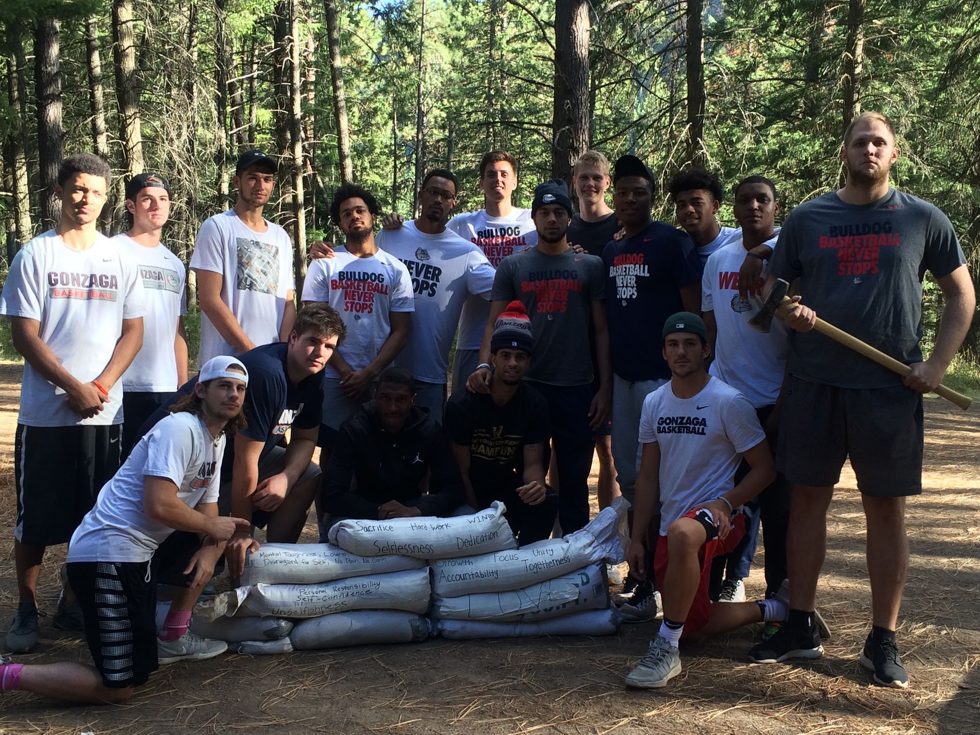 A group of young men are posing for a picture in the woods.