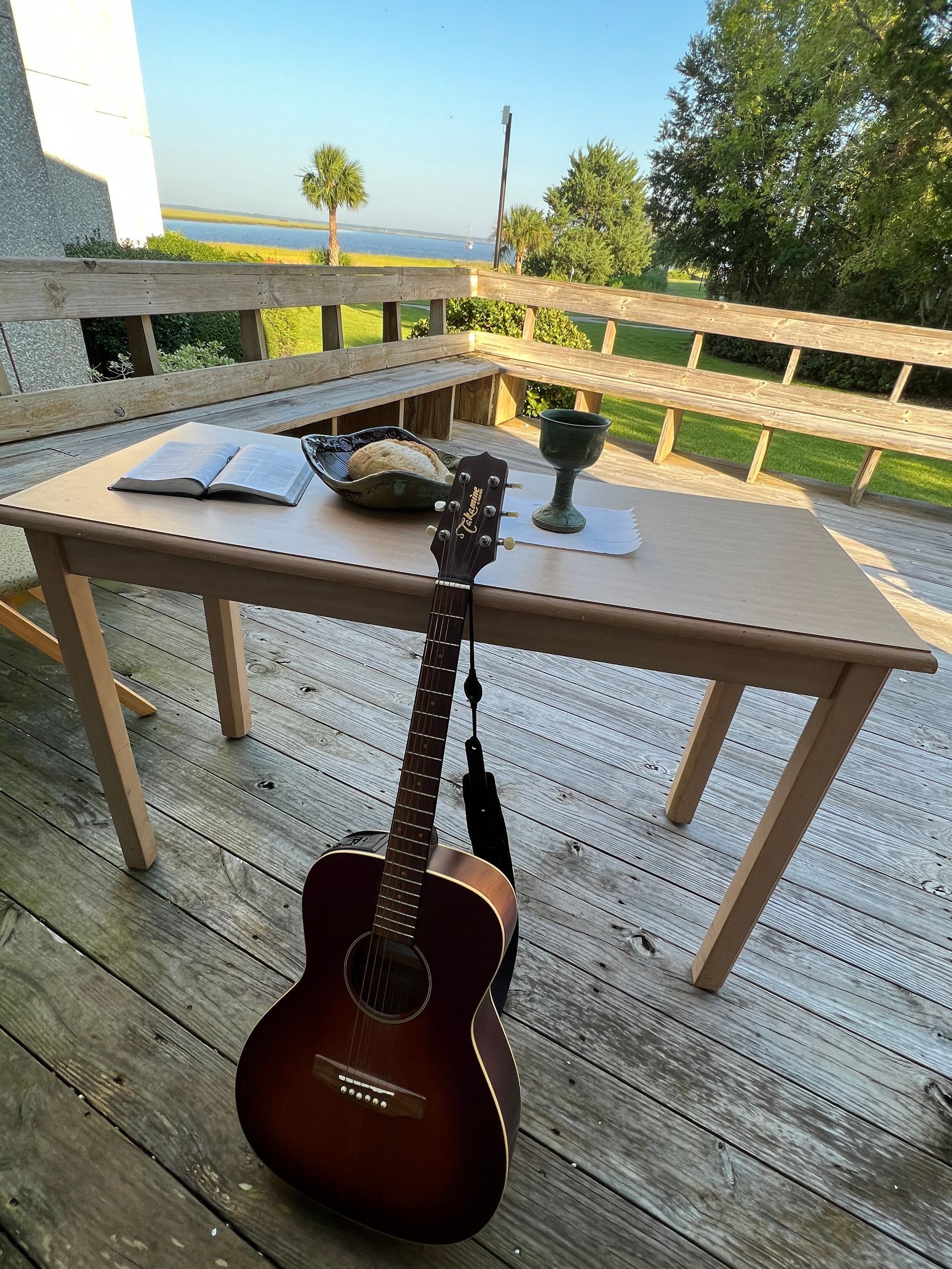 A guitar is sitting on a wooden table on a deck.