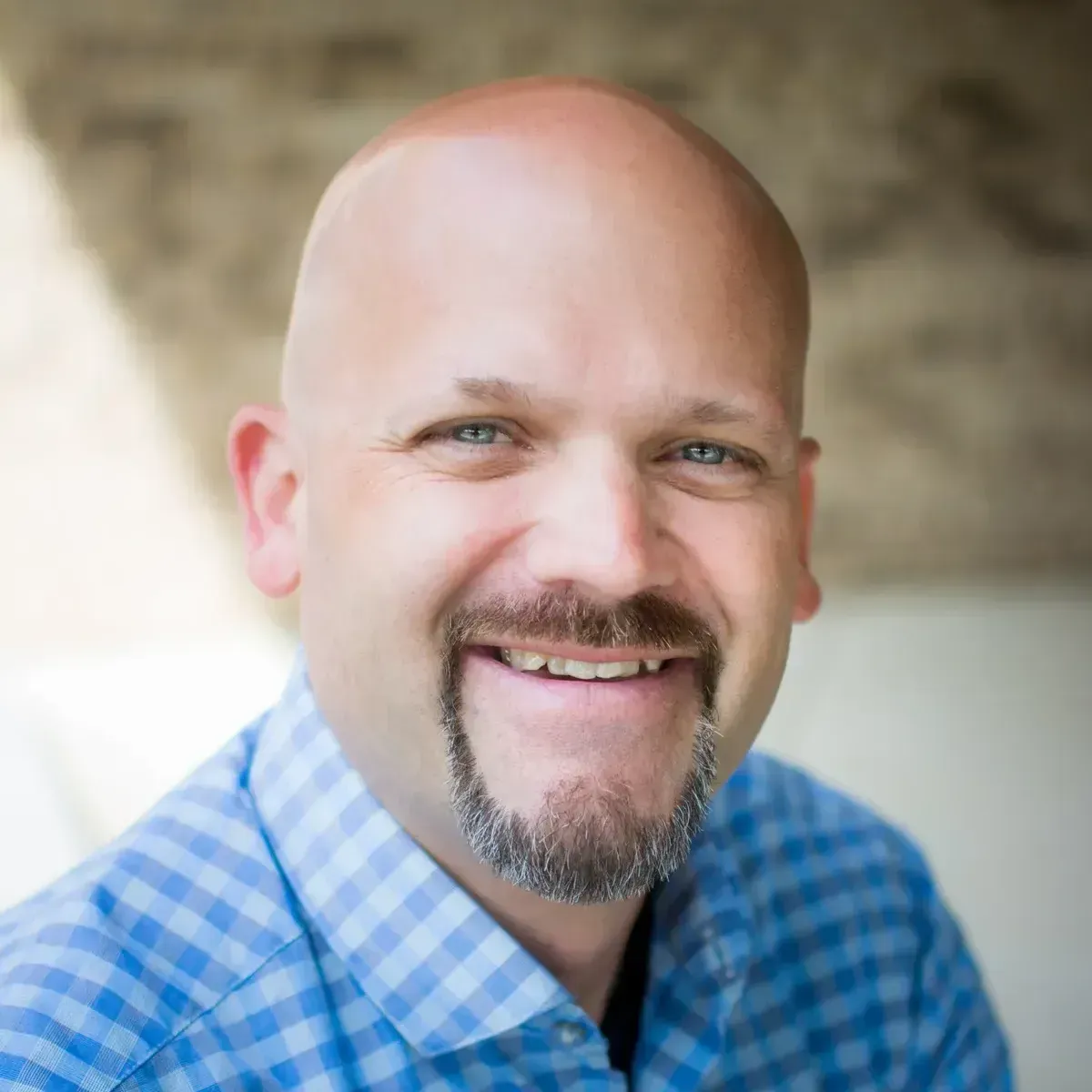 A bald man with a beard and mustache is smiling for the camera.