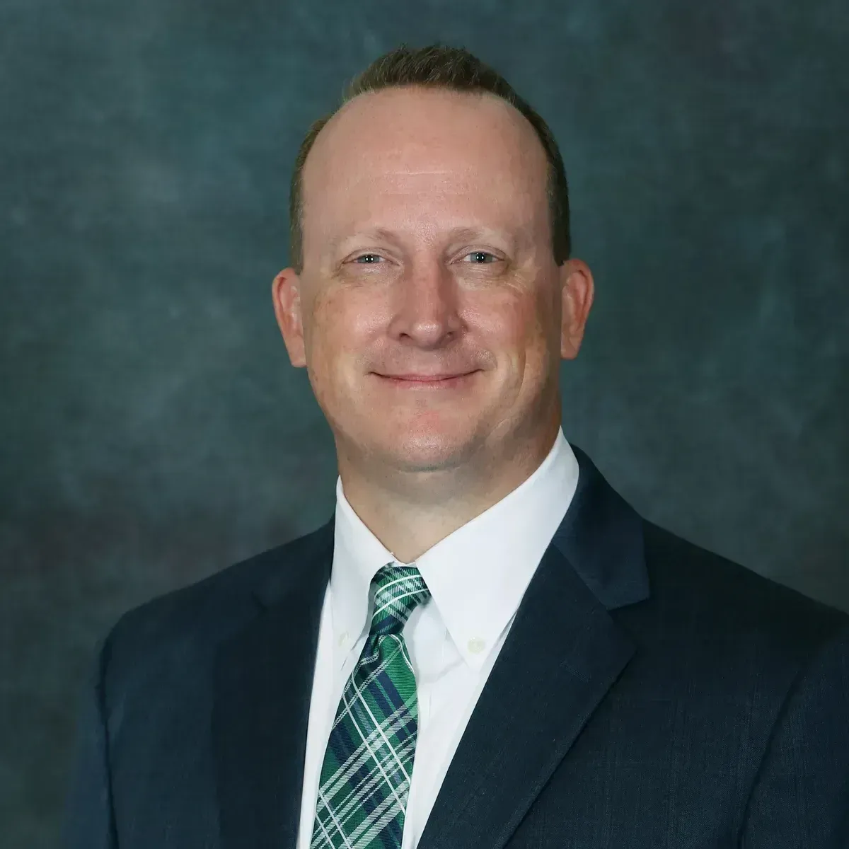 A man in a suit and tie is smiling for the camera