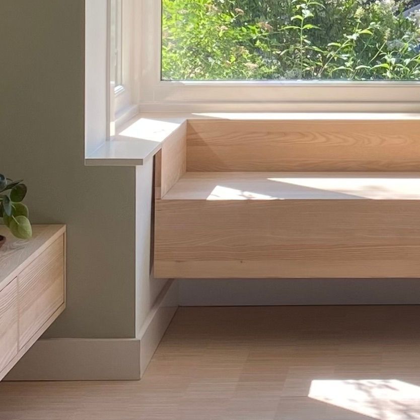 Een houten bankje staat naast een raam in een kamer.