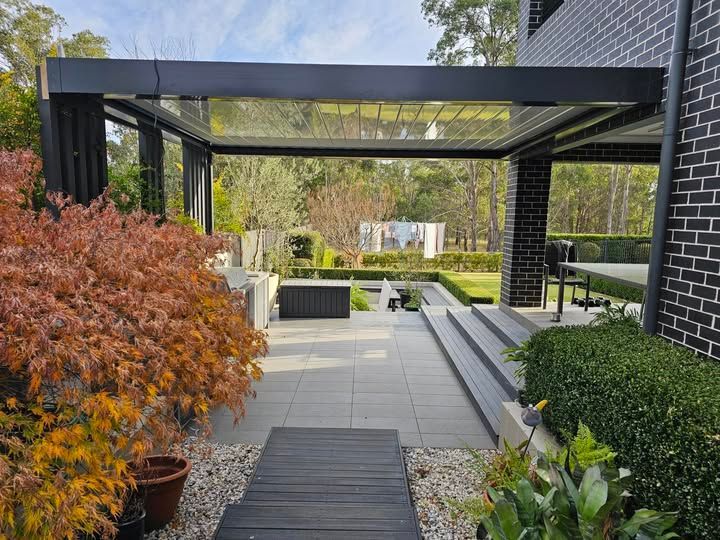 Patio With Retractable Roof, Bordered by Garden and Dark Brick Wall — Narellan Home Improvement Centre In Orange, NSW