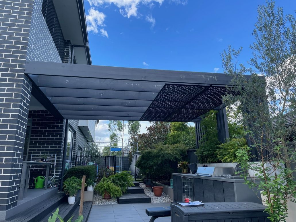Black Pergola Over a Patio With Plants — Narellan Home Improvement Centre In Dubbo, NSW