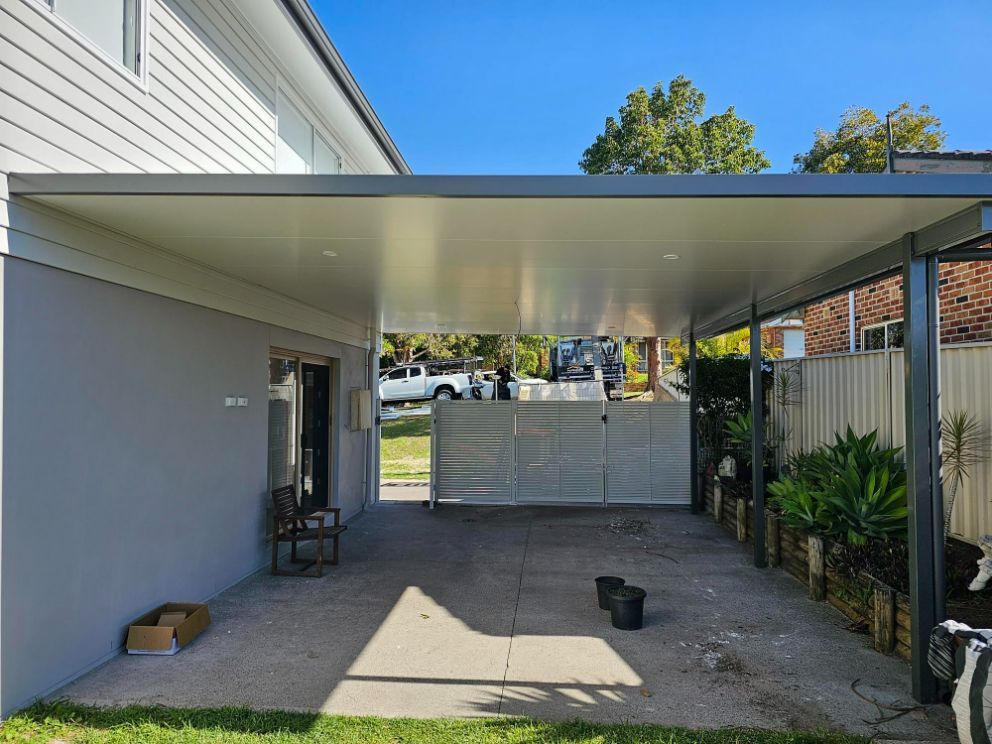 Carport Attached to a Gray House With a Concrete Driveway — Narellan Home Improvement Centre In Wollongong, NSW
