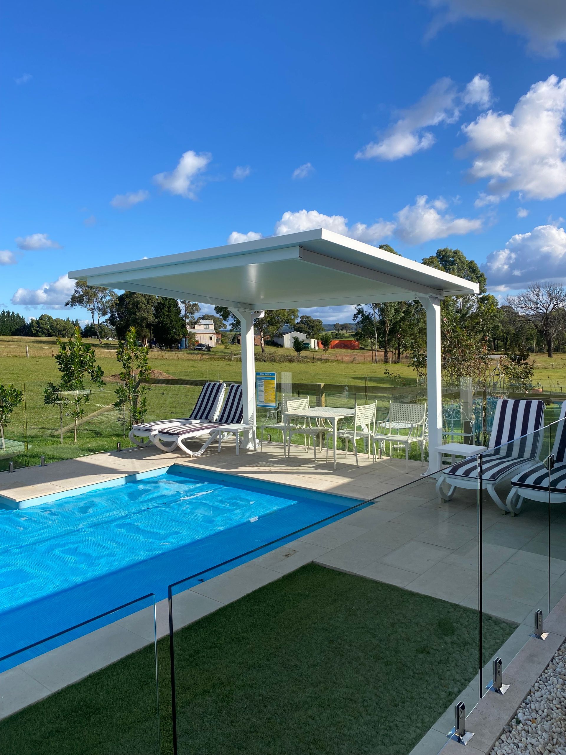 Covered Patio With Brick Base, Brown Railing, Cream Walls, and Green Lawn — Narellan Home Improvement Centre In Narellan, NSW