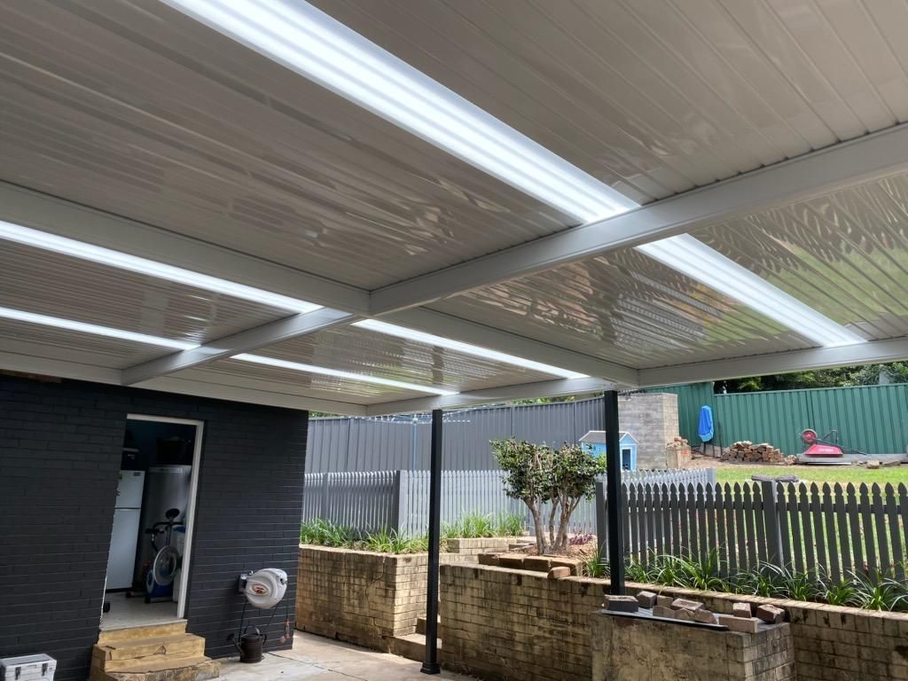 White Patio Roof Over a Brick and Black Walled Outdoor Space — Narellan Home Improvement Centre In Wollongong, NSW
