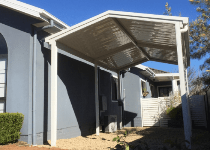 A Beige, Slatted Aluminum Pergola Cover Attached to a Blue House — Narellan Home Improvement Centre In Narellan, NSW