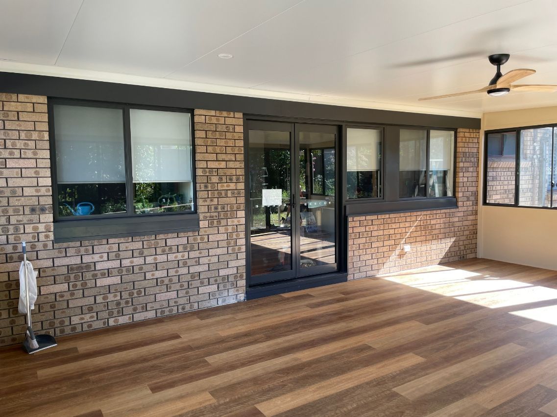 Sunlit Covered Patio With Sliding Glass Doors, and Wooden Flooring — Narellan Home Improvement Centre In Narellan, NSW