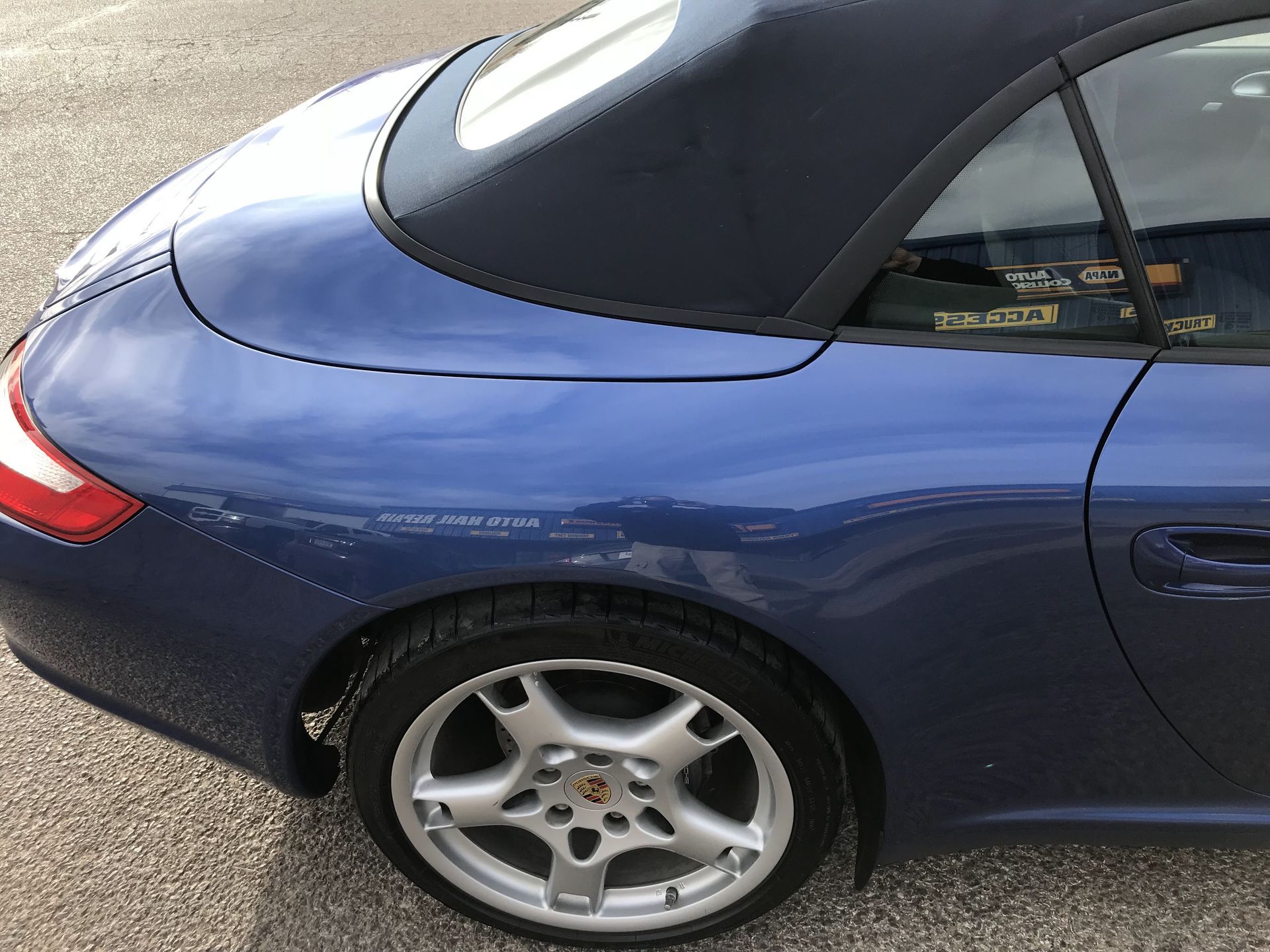 Blue sports car rear side with black soft top and silver wheel parked on pavement | Texas Carworx