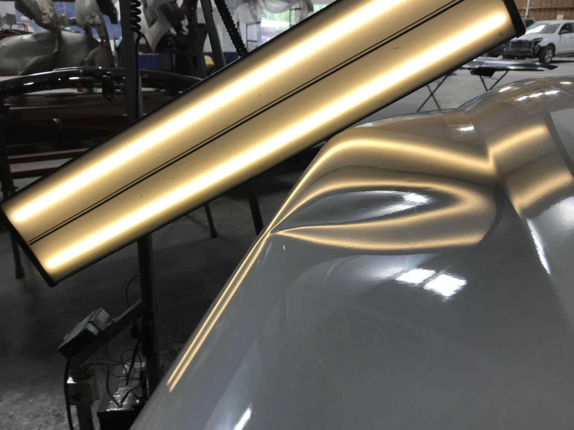 Gold trim light reflecting on a gray car hood at a workshop | Texas Carworx