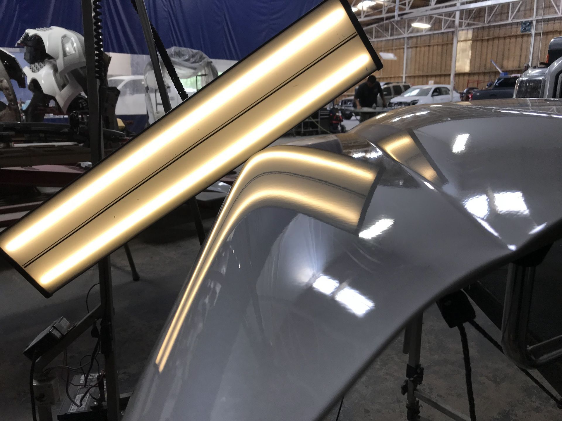 Close-up of a silver car hood being wrapped or polished under workshop lights | Texas Carworx
