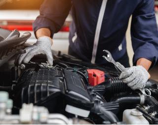 Mechanic working on a car engine with a wrench in a garage | Texas Carworx