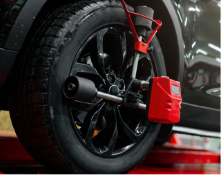 Close-up of a car wheel with a red brake caliper and clamp-style wheel lock installed indoors. | Texas Carworx