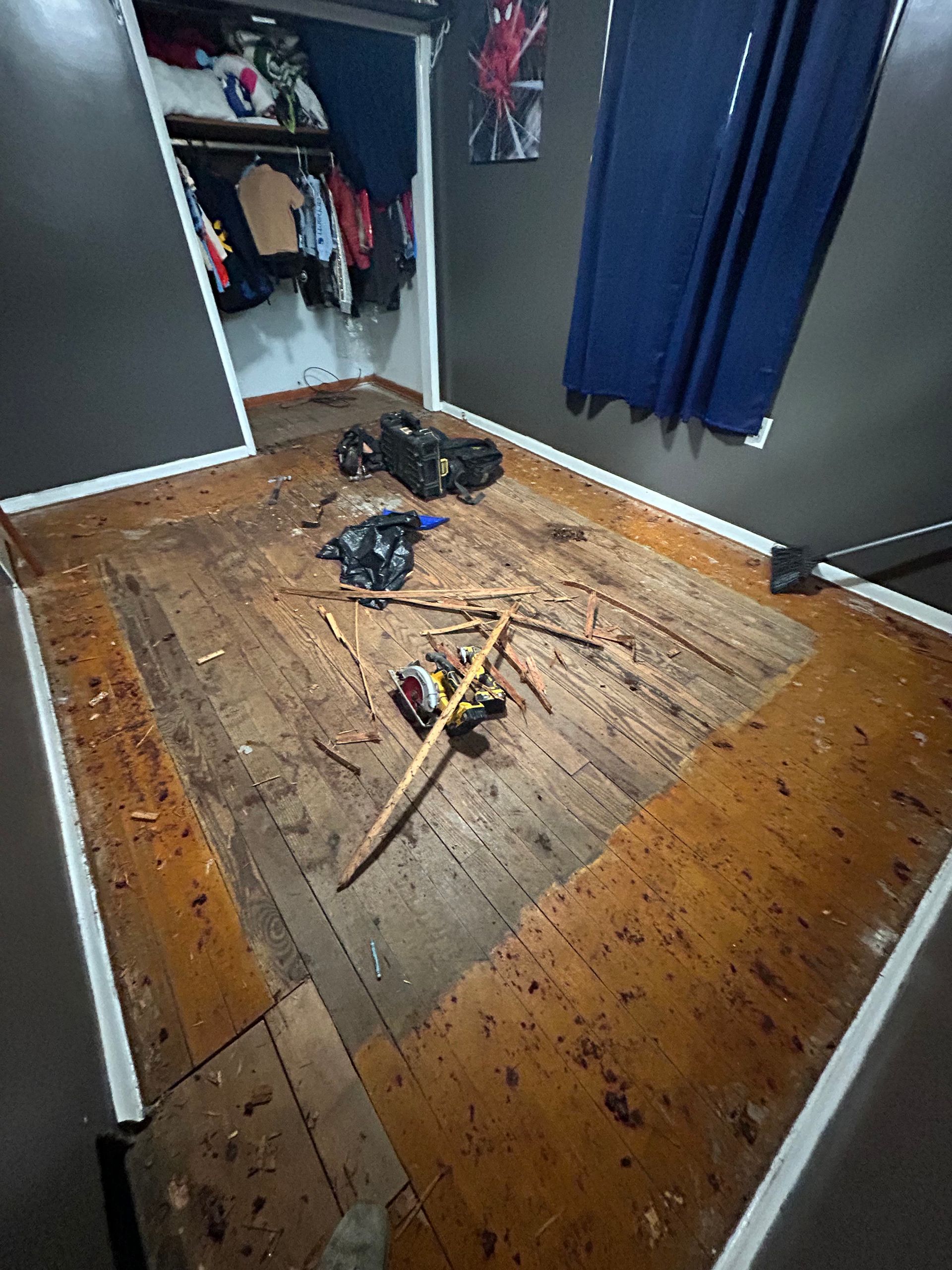 Damaged room with wood flooring, debris, and open closet.