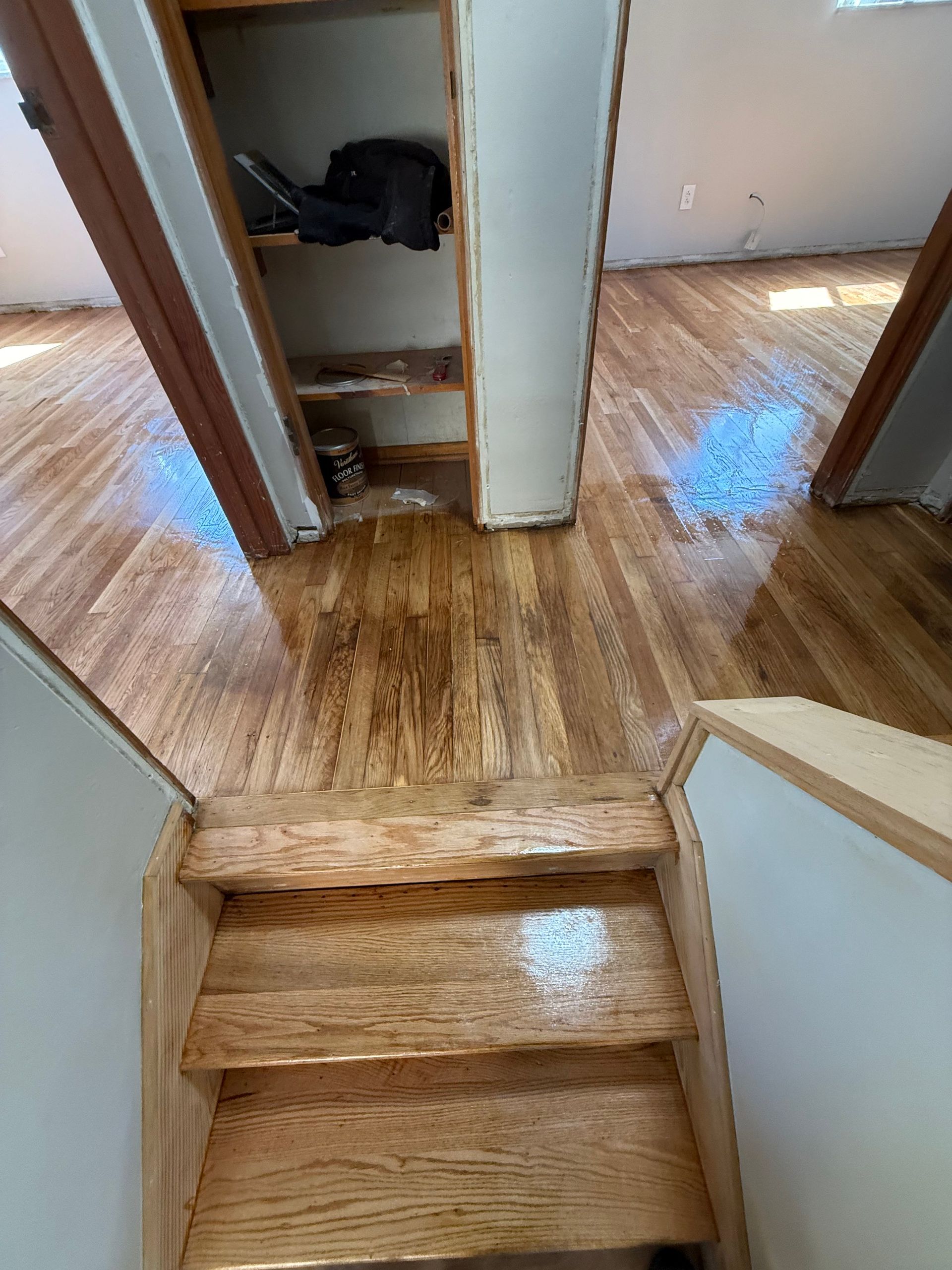Wooden staircase leading up to hardwood floors in a sunlit room, with a built-in storage area.