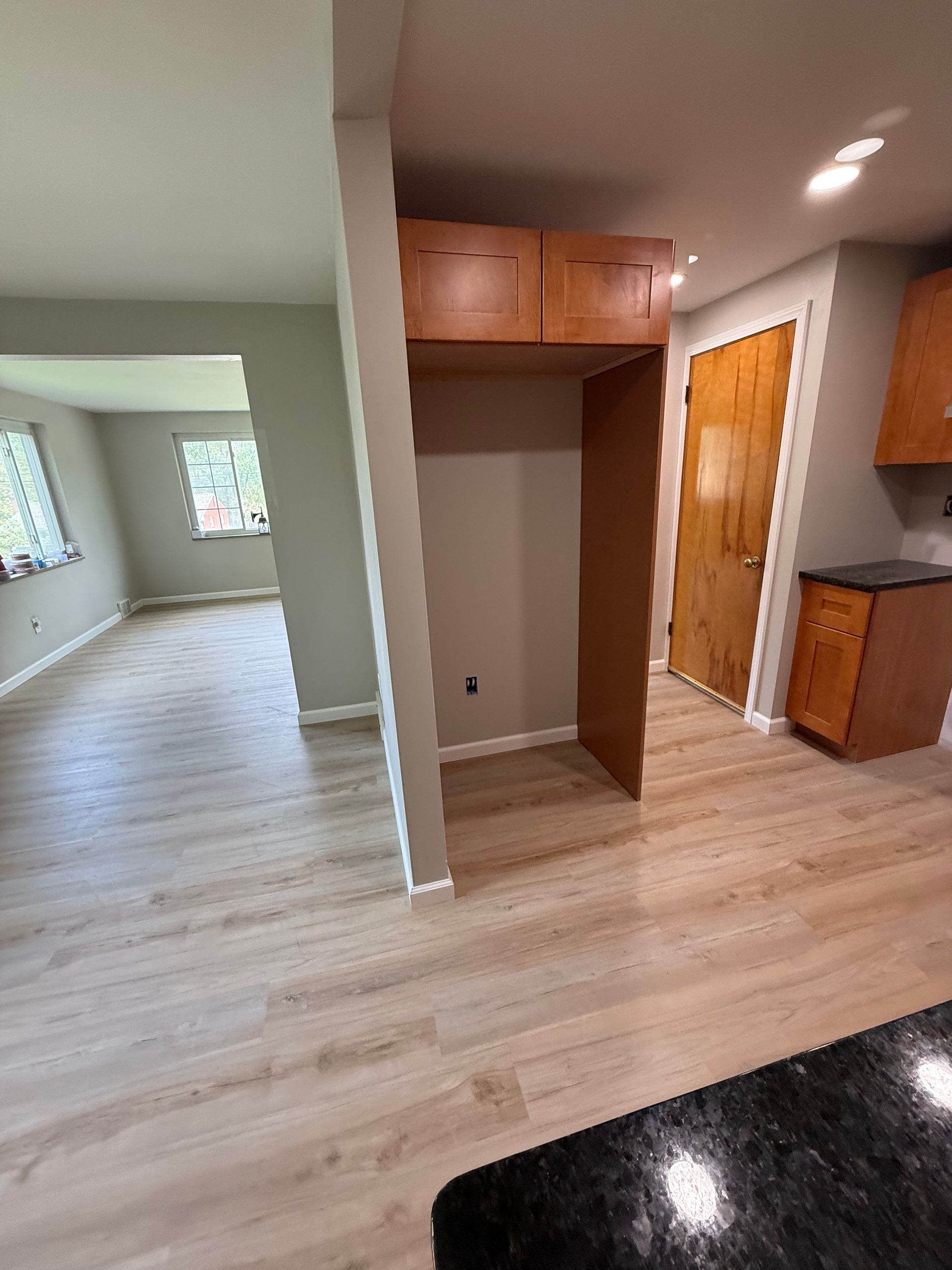 Kitchen area with empty refrigerator cabinet. Light wood flooring, neutral walls.