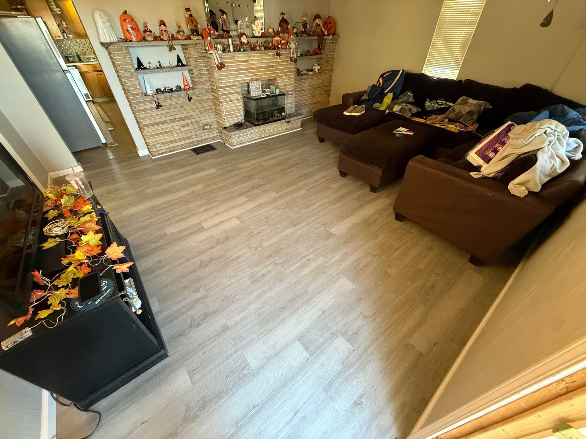 Living room with a sectional sofa, fireplace, and TV stand, decorated for autumn.