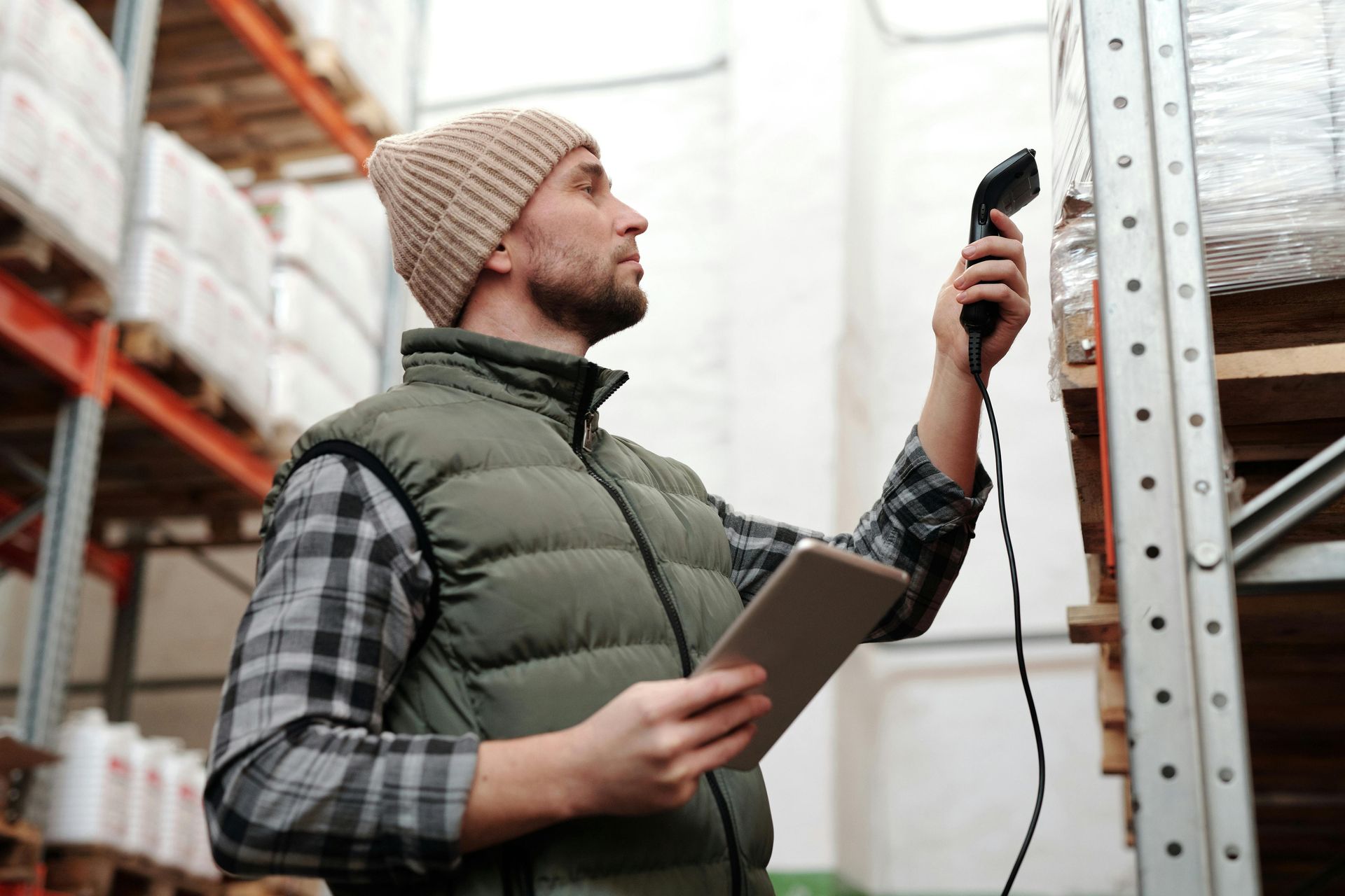 Man in warehouse scanning inventory with tablet.
