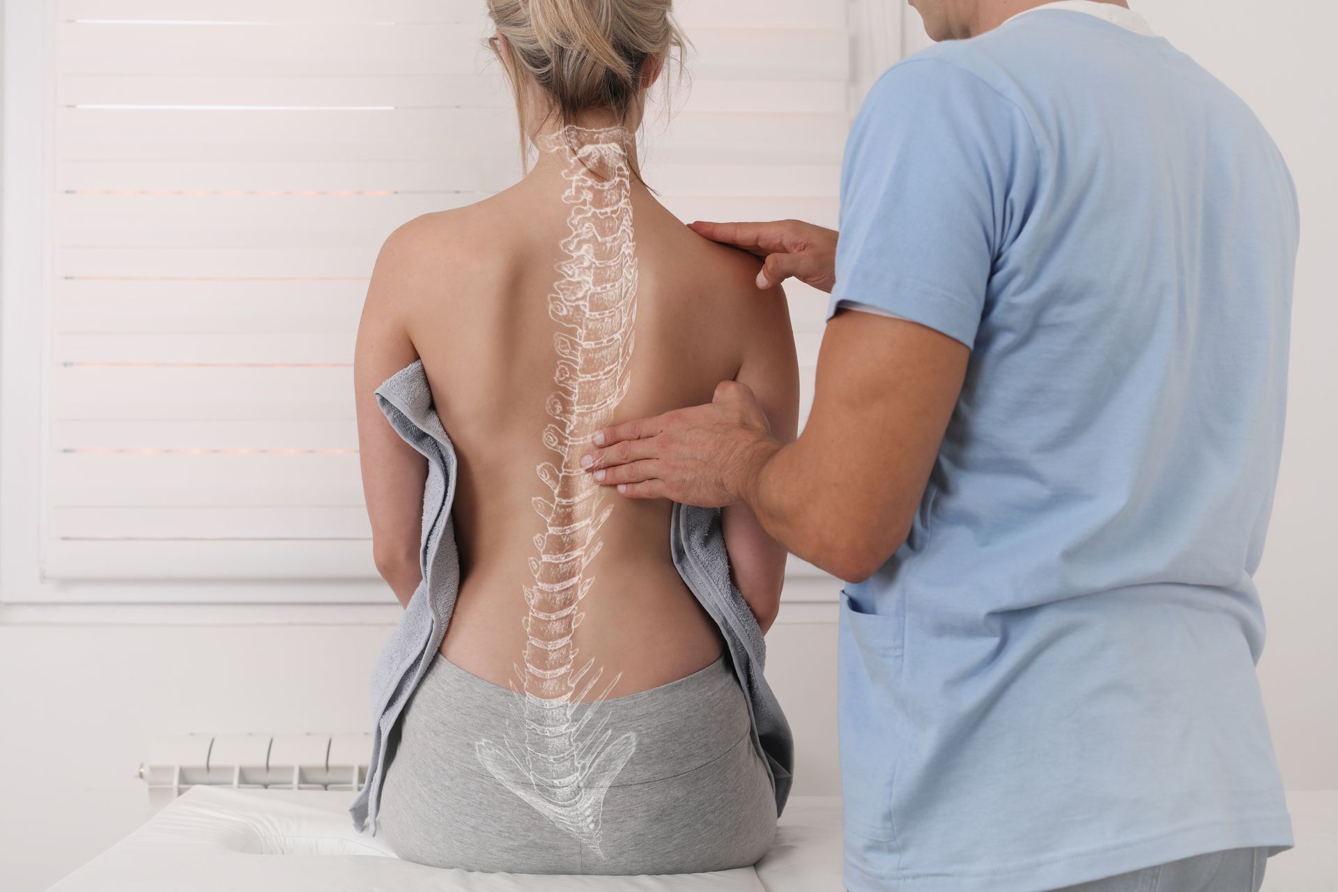 Woman getting spine exam by a man in a medical office. White overlaid spine model.