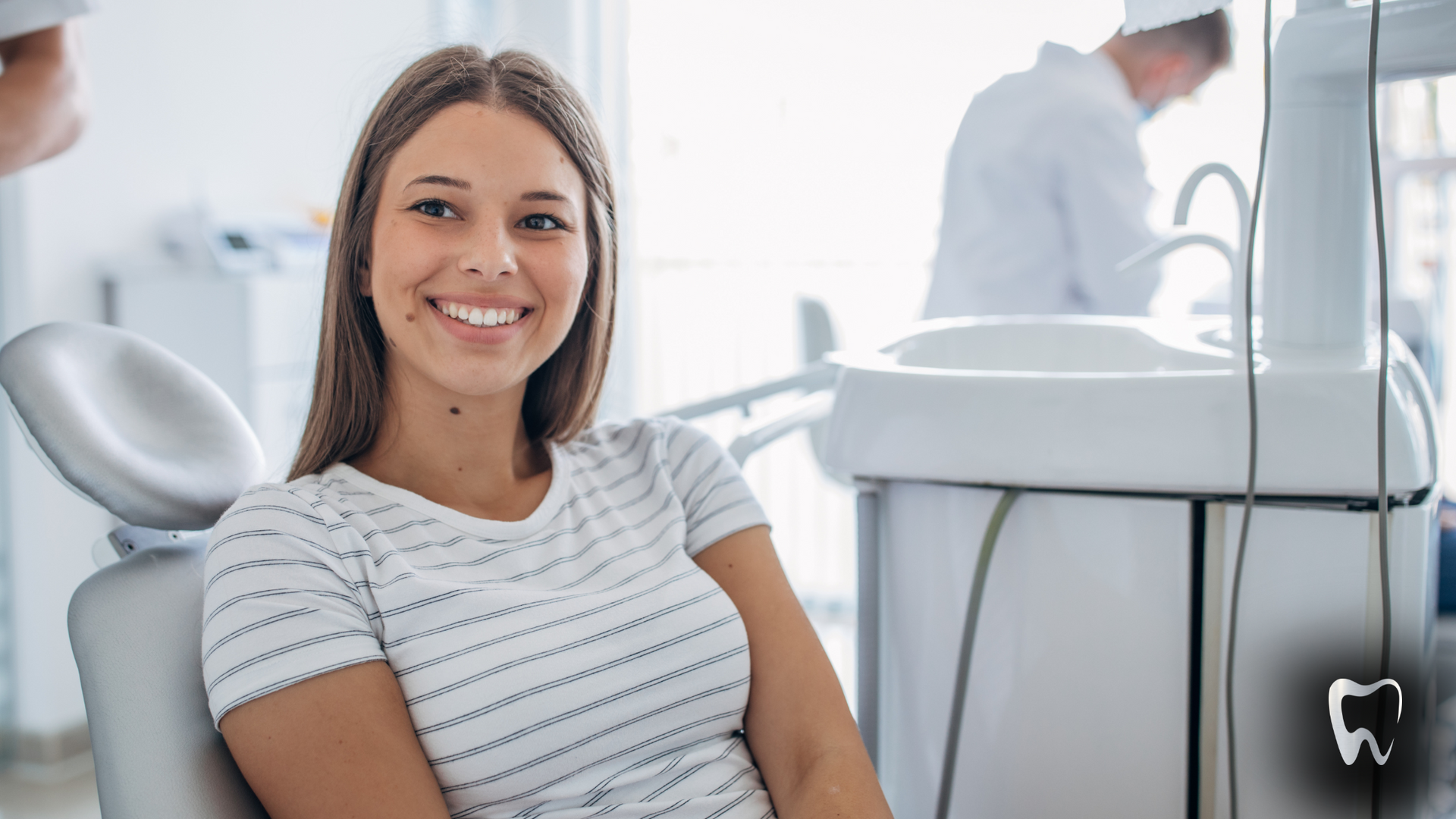 A woman is smiling while sitting in a dental chair.