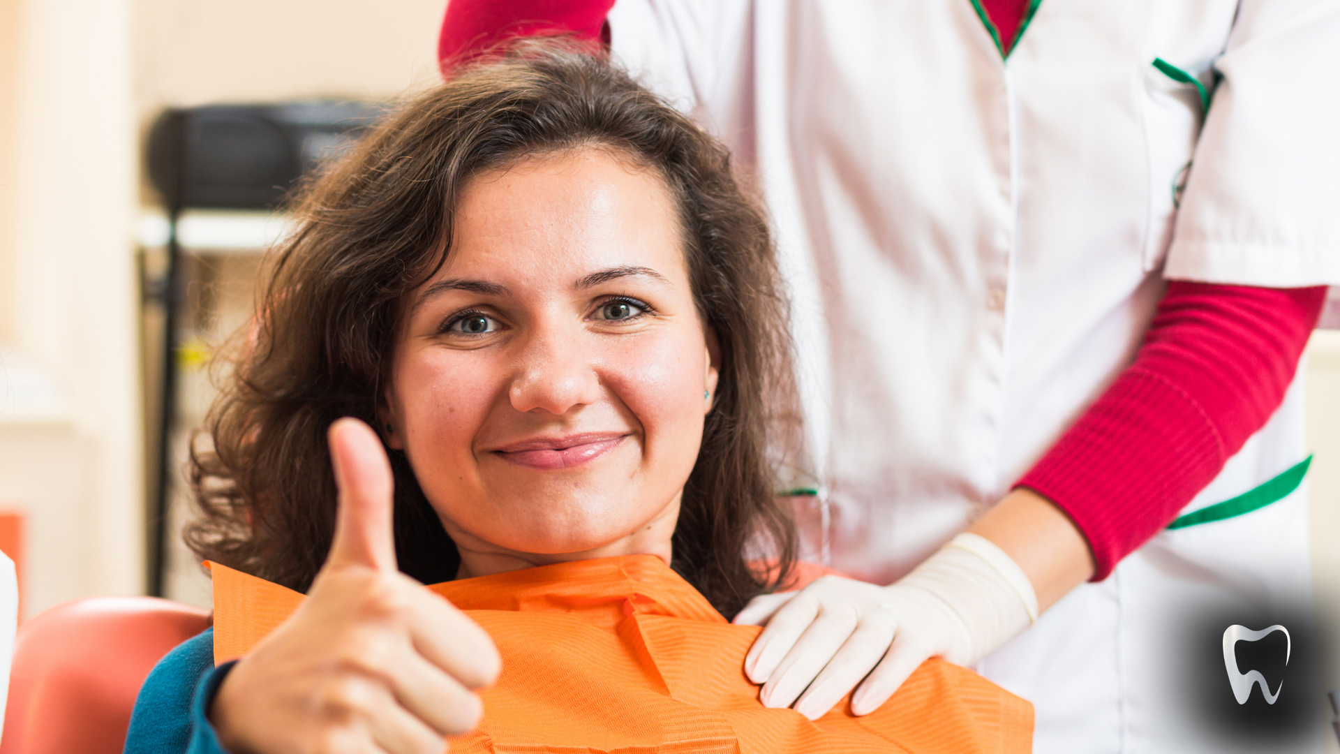 A woman is giving a thumbs up while sitting in a dental chair.