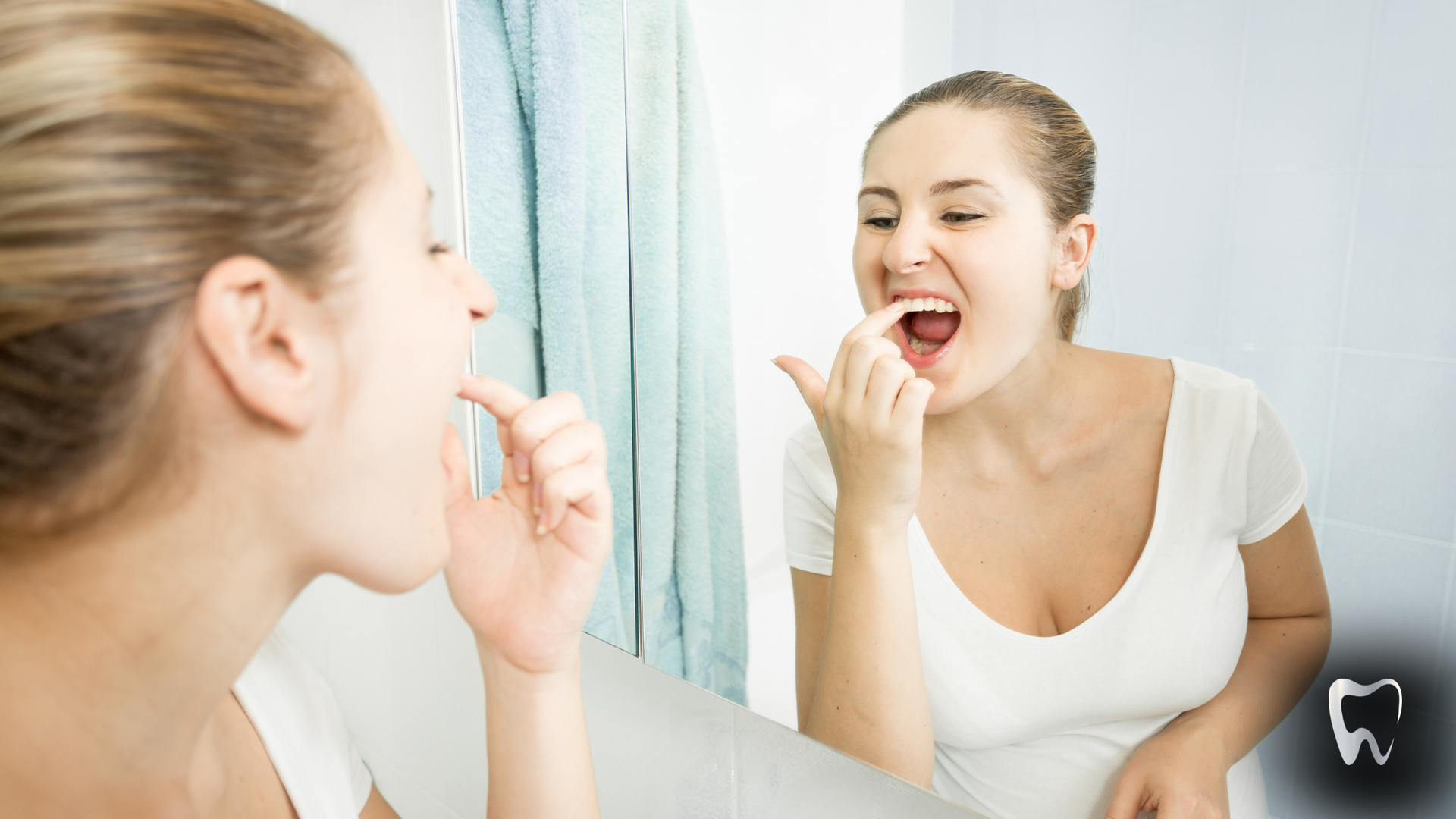 A woman is brushing her teeth in front of a mirror.