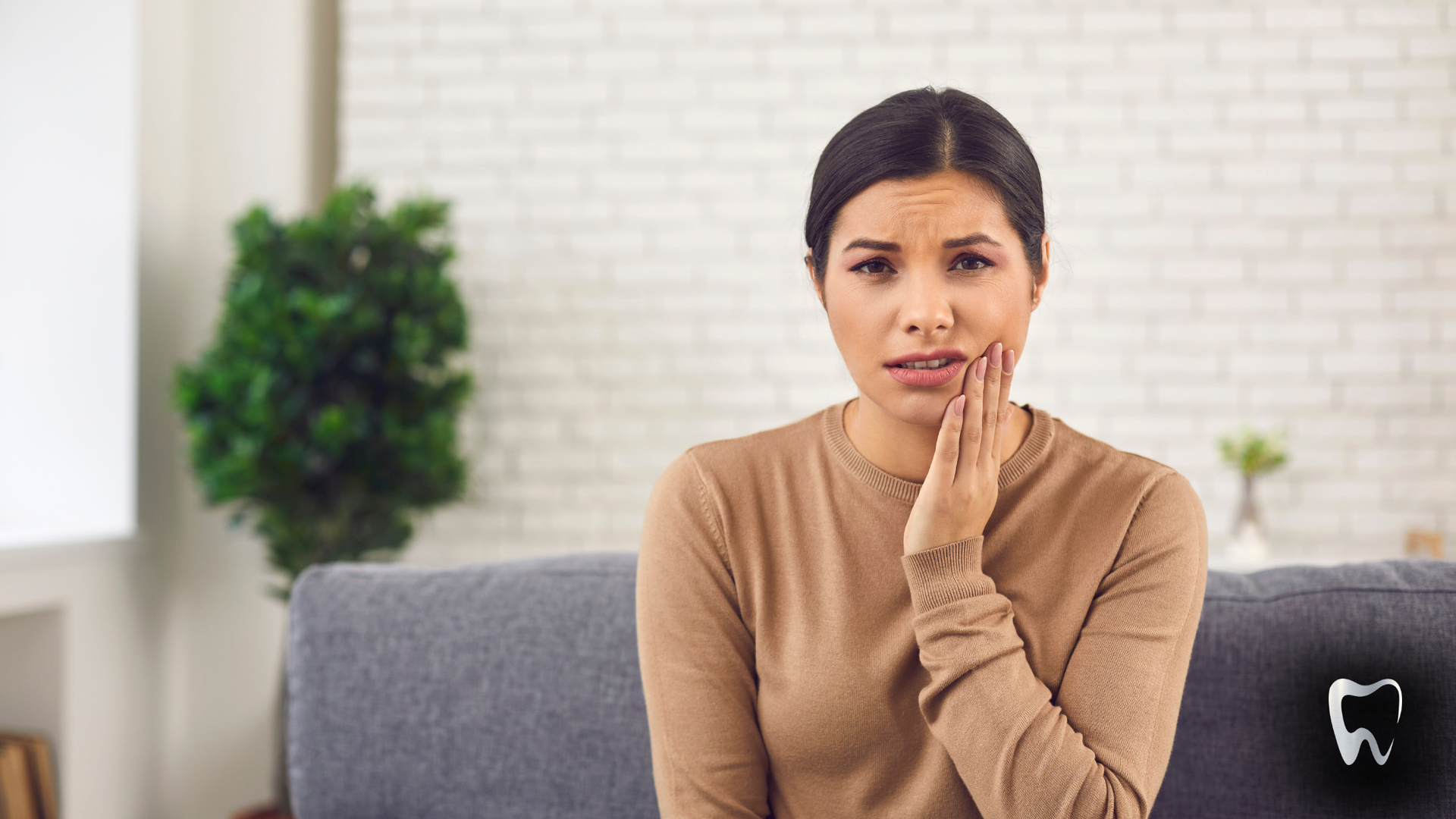 A woman is sitting on a couch with a toothache.