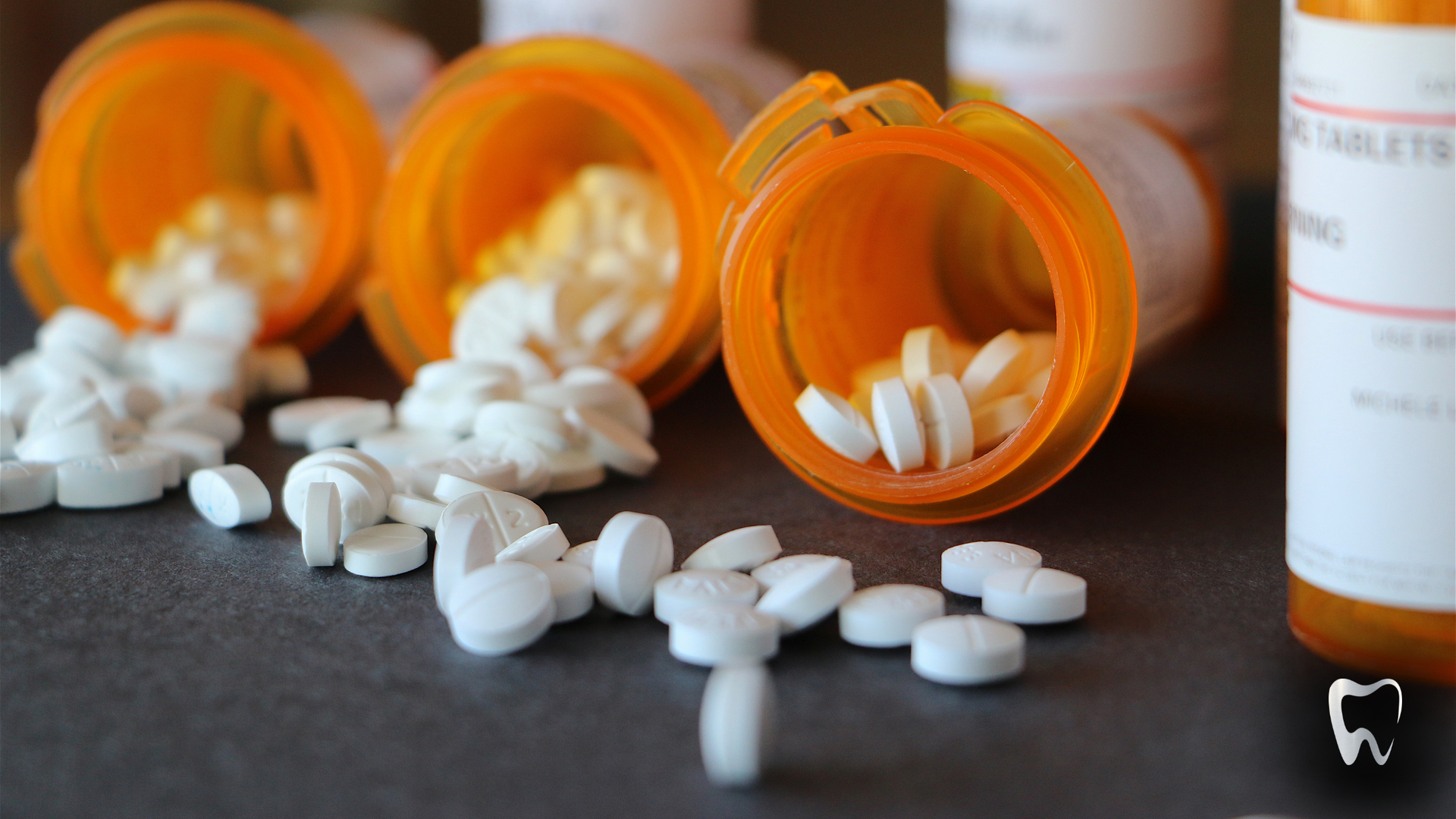 A bunch of pills are spilling out of bottles on a table.