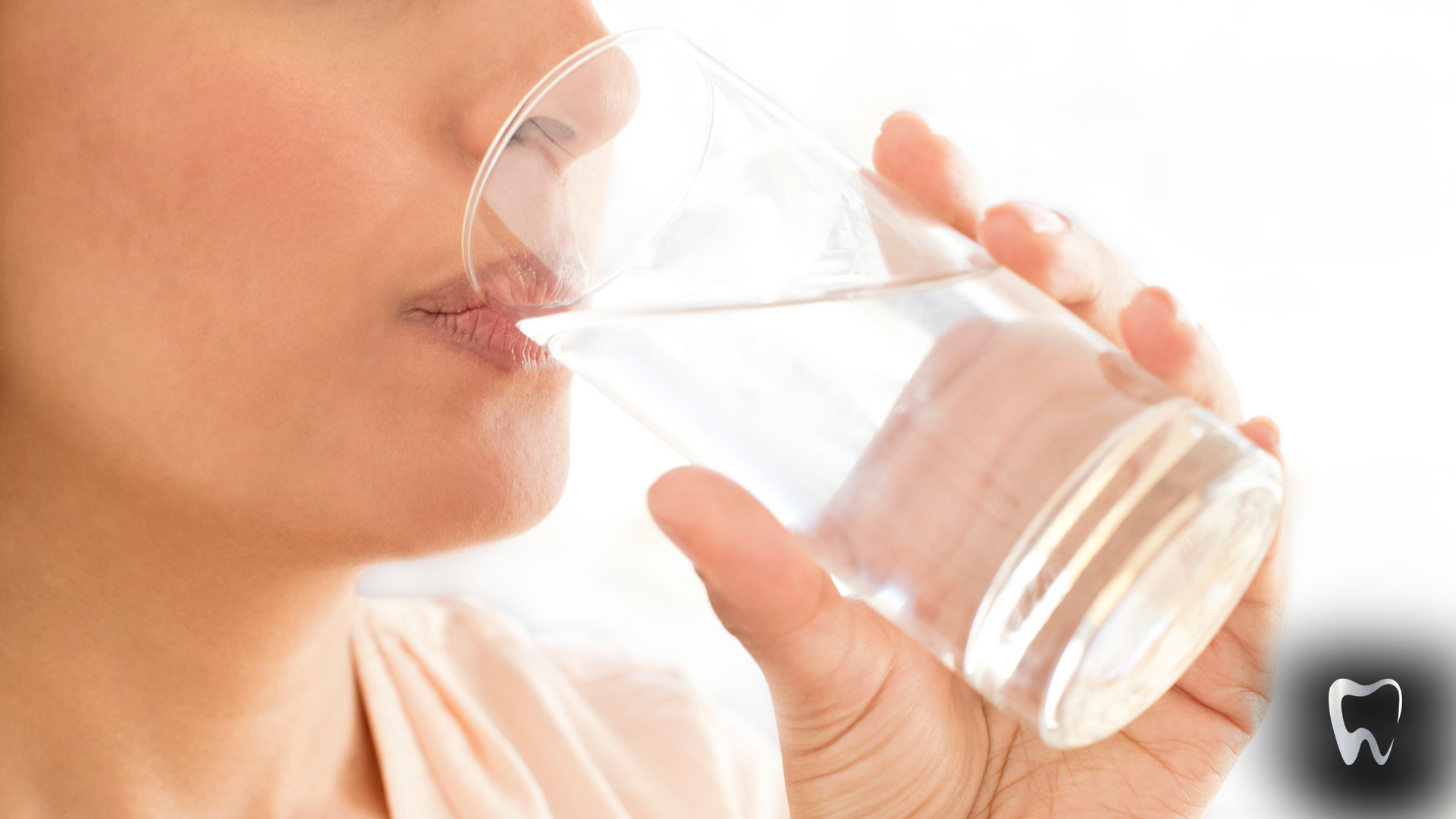 A woman is drinking a glass of water.