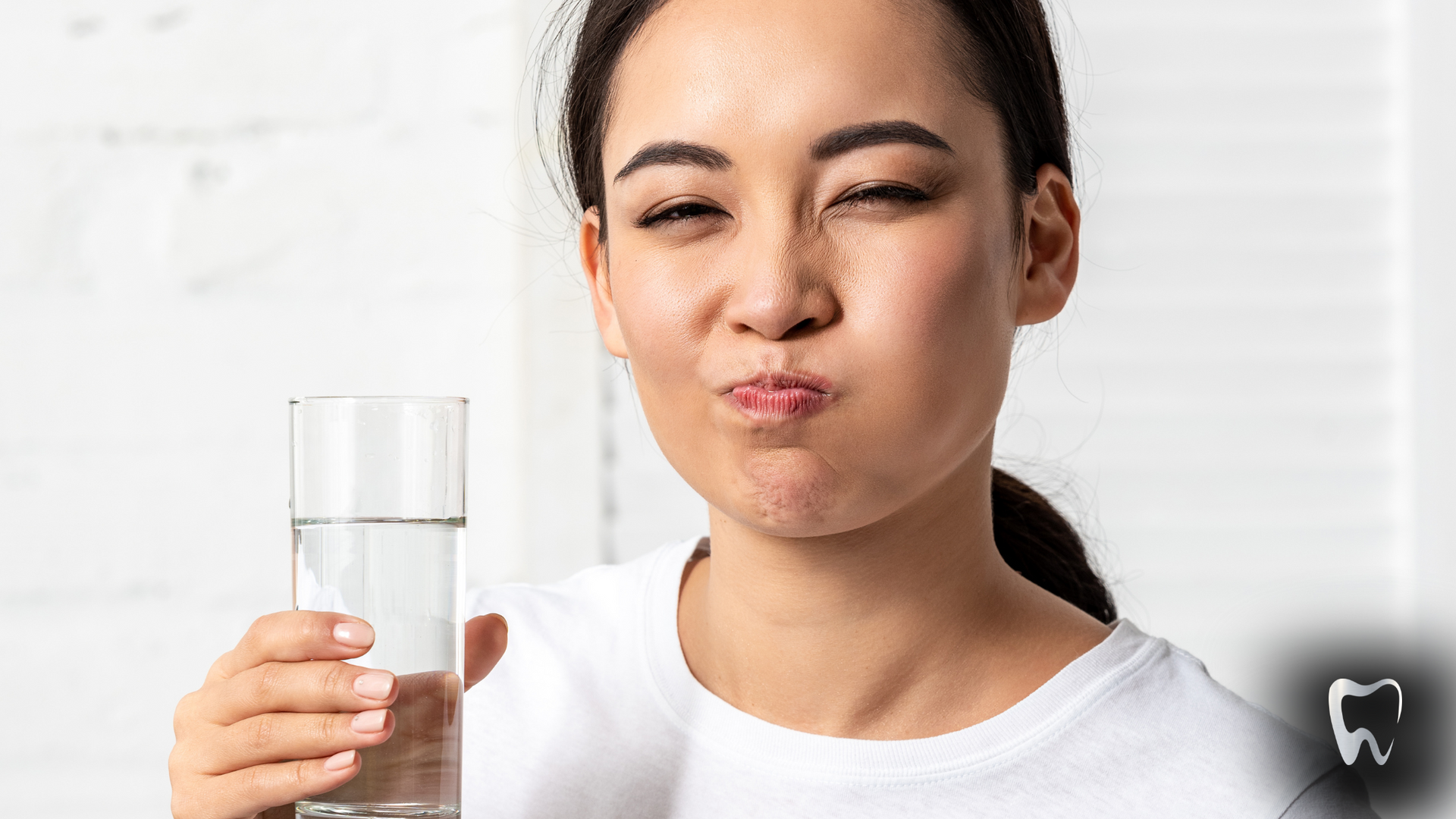 A woman is holding a glass of water in her hand.