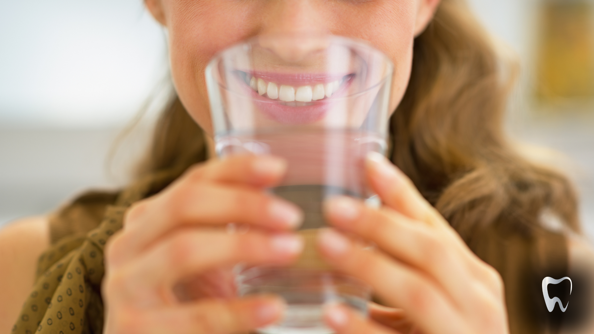 A woman is drinking a glass of water with her mouth open.